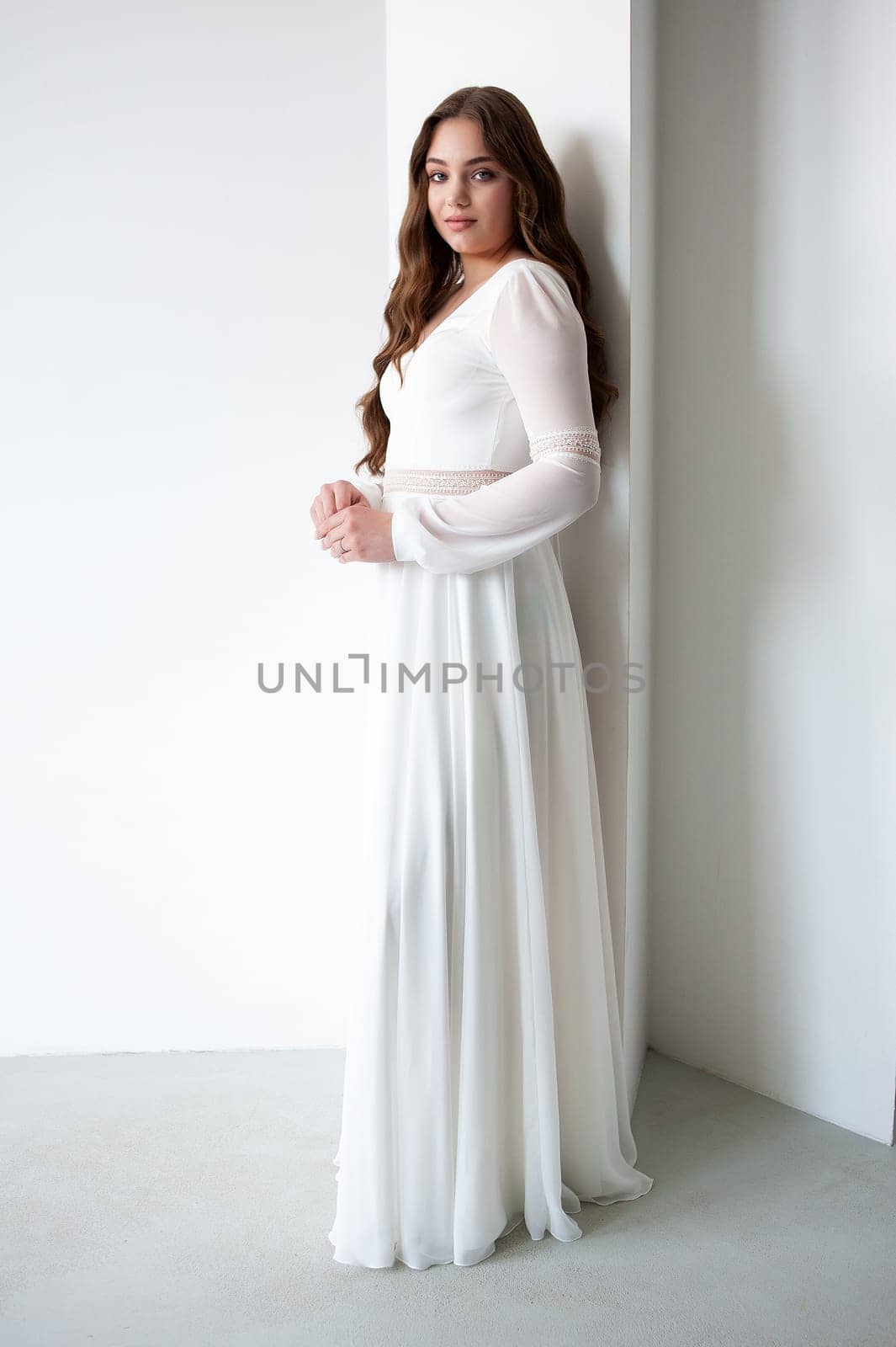 portrait of beautiful young woman in white wedding dress posing in studio