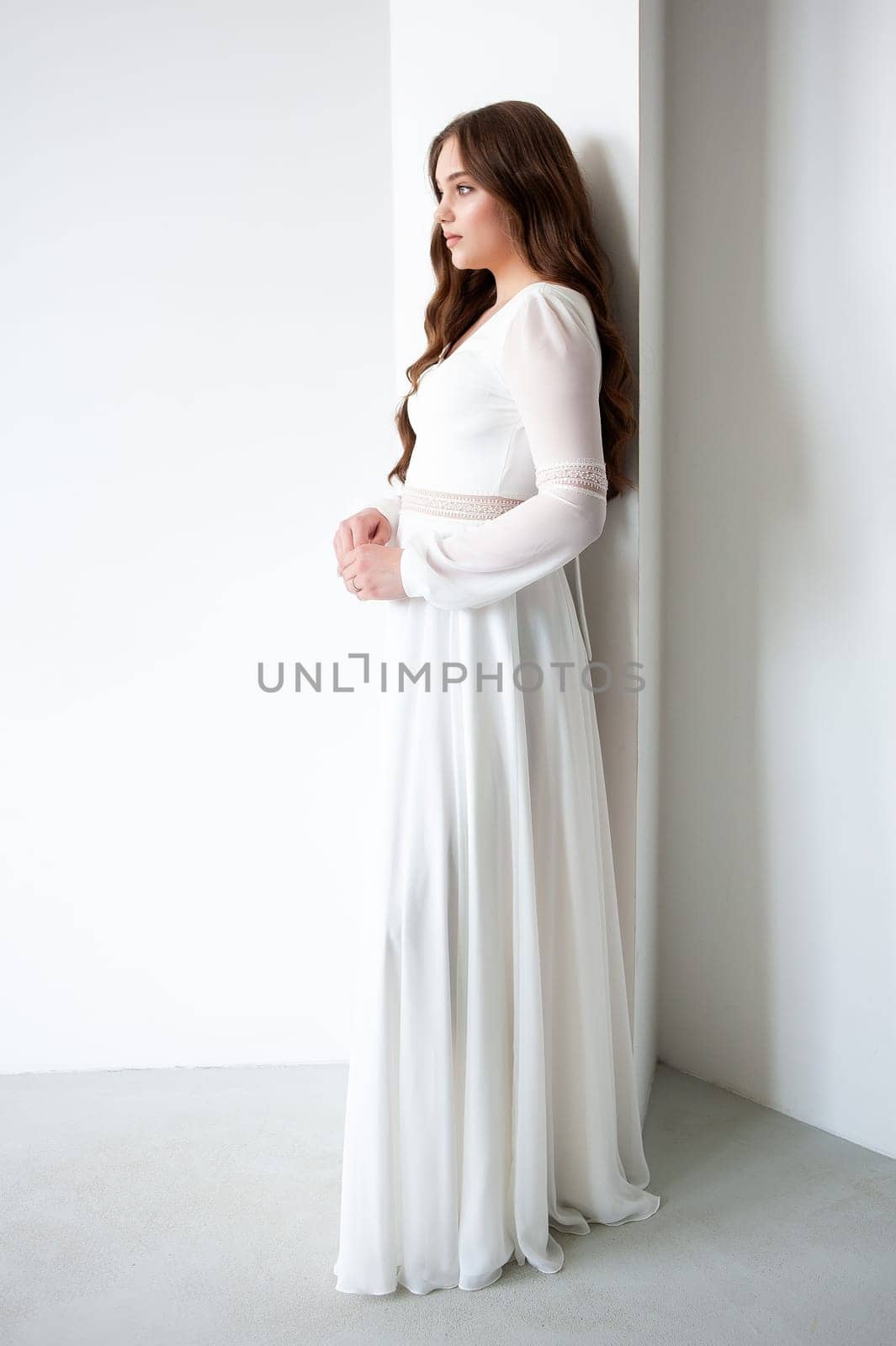 portrait of beautiful young woman in white wedding dress posing in studio