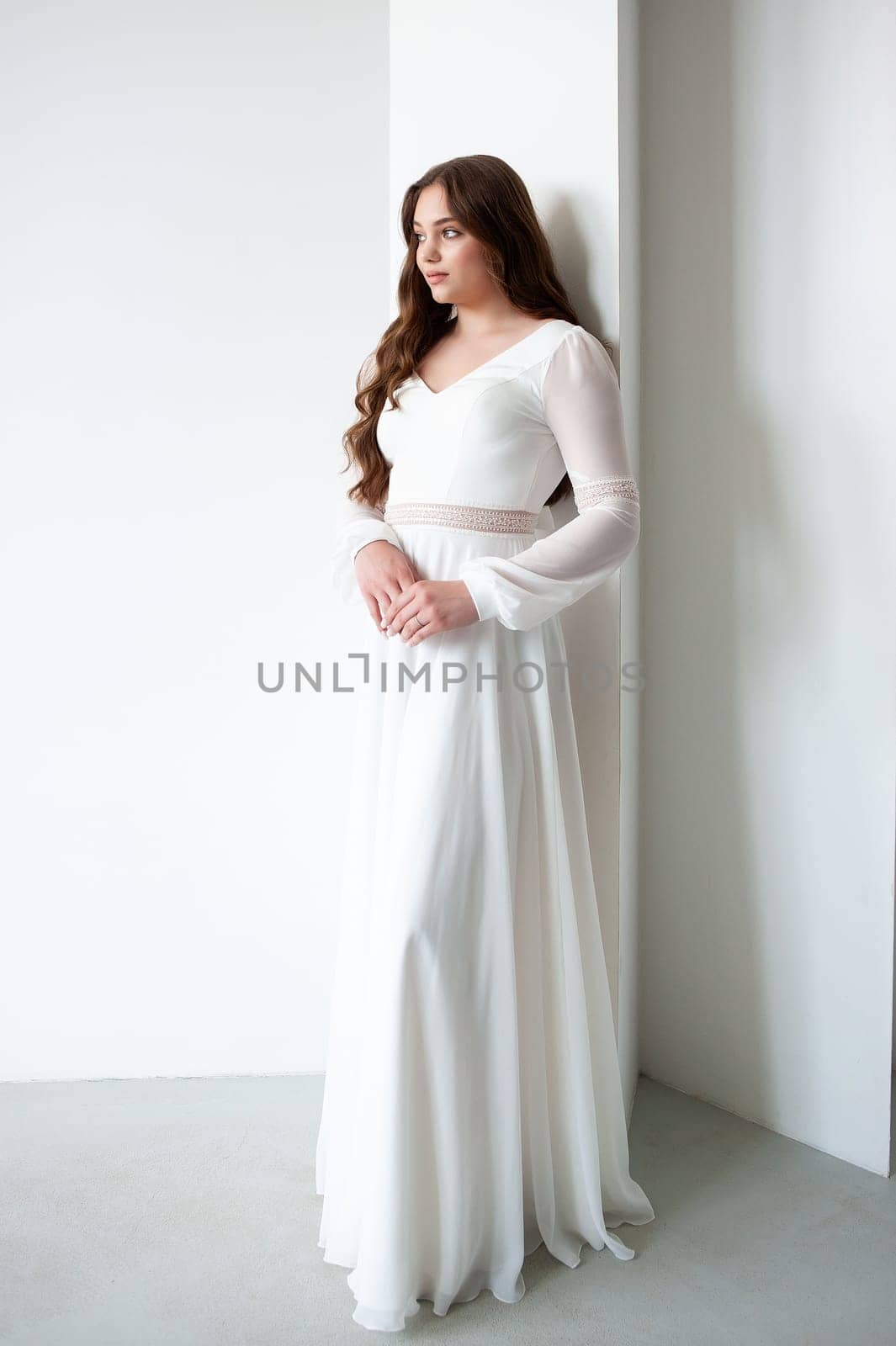 portrait of beautiful young woman in white wedding dress posing in studio