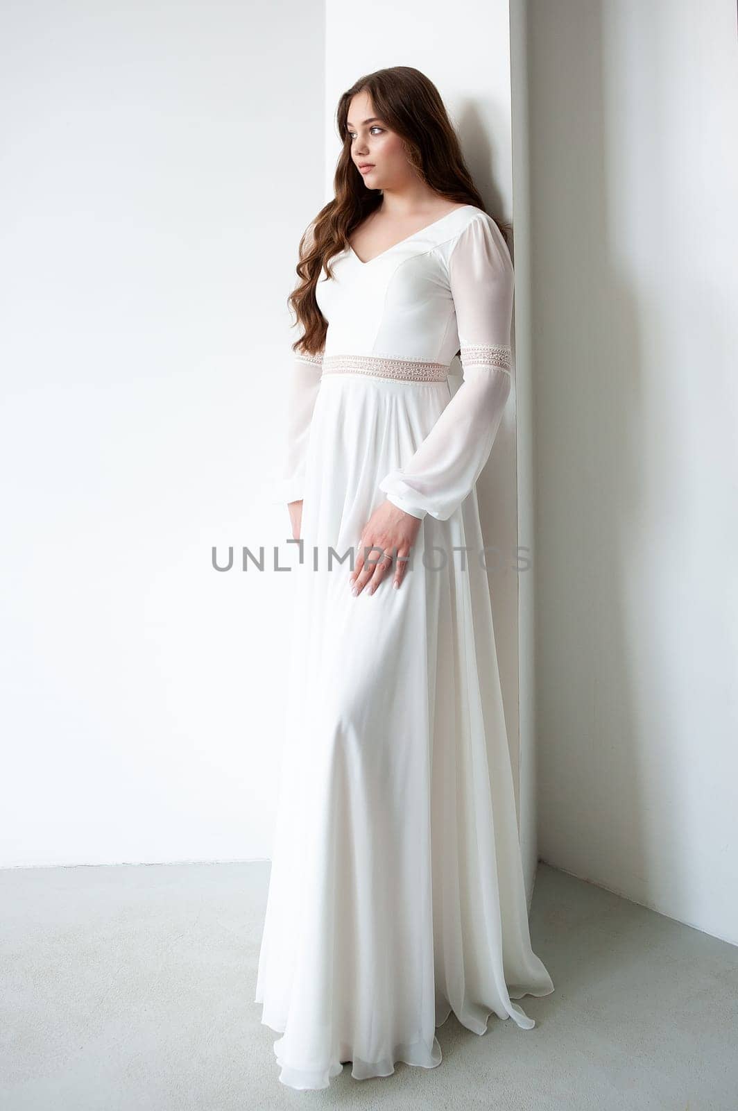 portrait of beautiful young woman in white wedding dress posing in studio