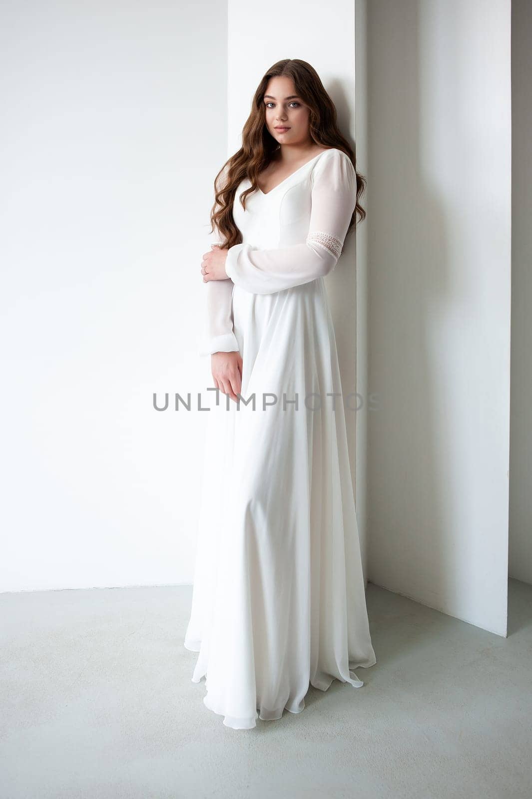 portrait of beautiful young woman in white wedding dress posing in studio