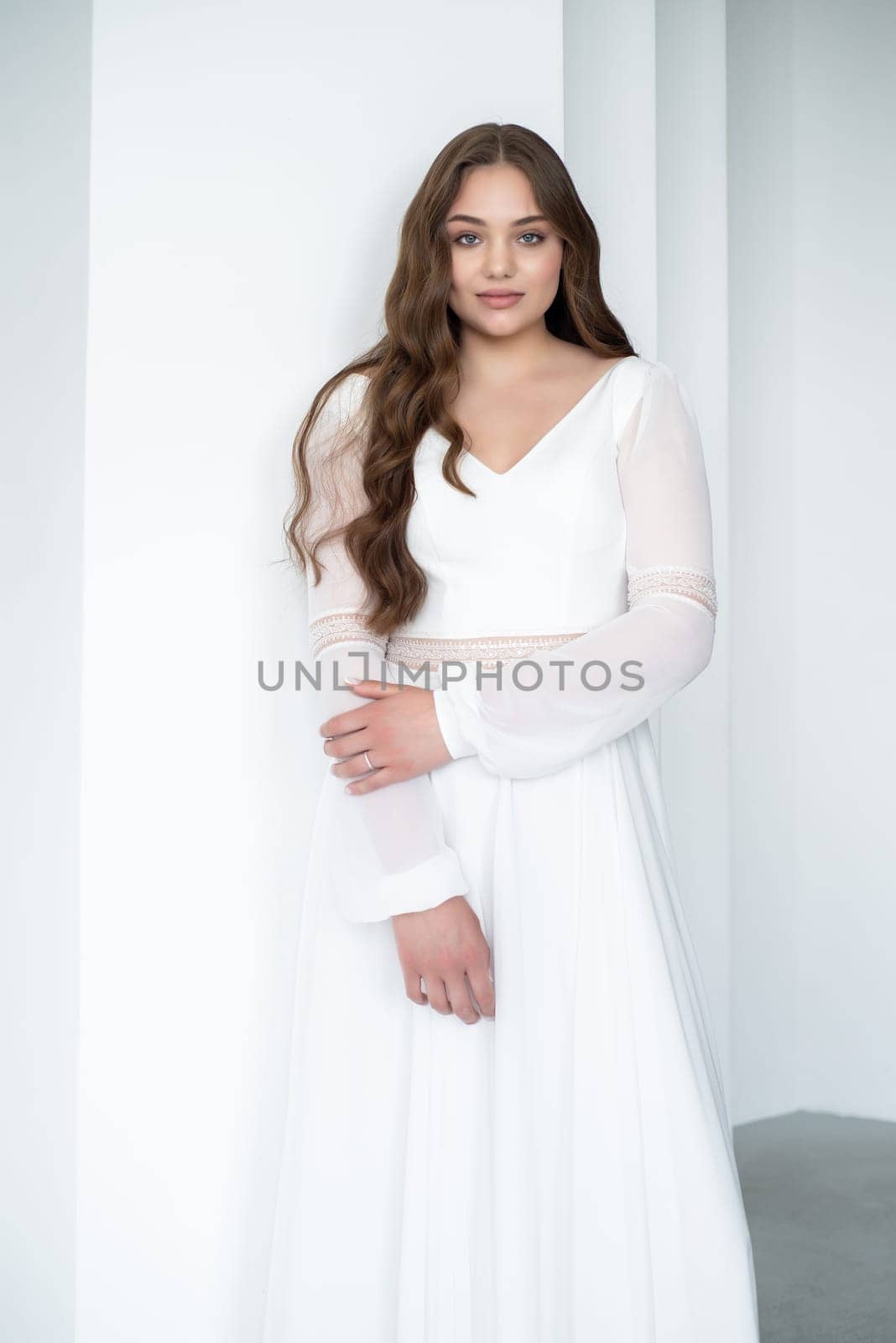 portrait of beautiful young woman in white wedding dress posing in studio