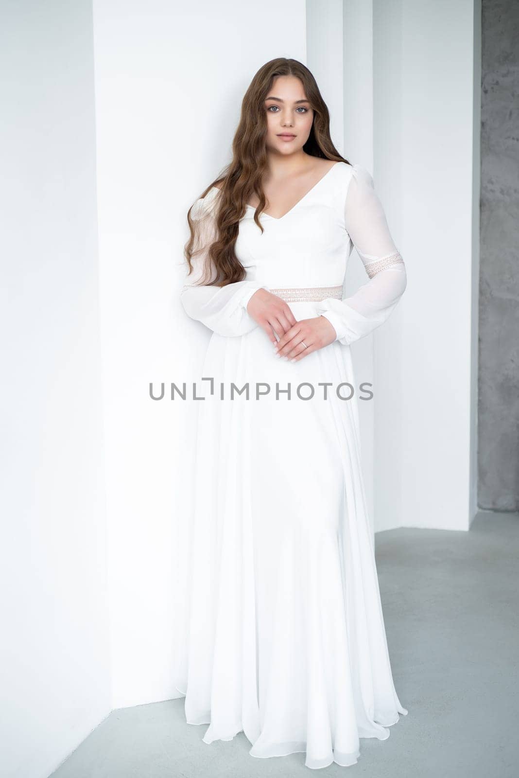 portrait of beautiful young woman in white wedding dress posing in studio