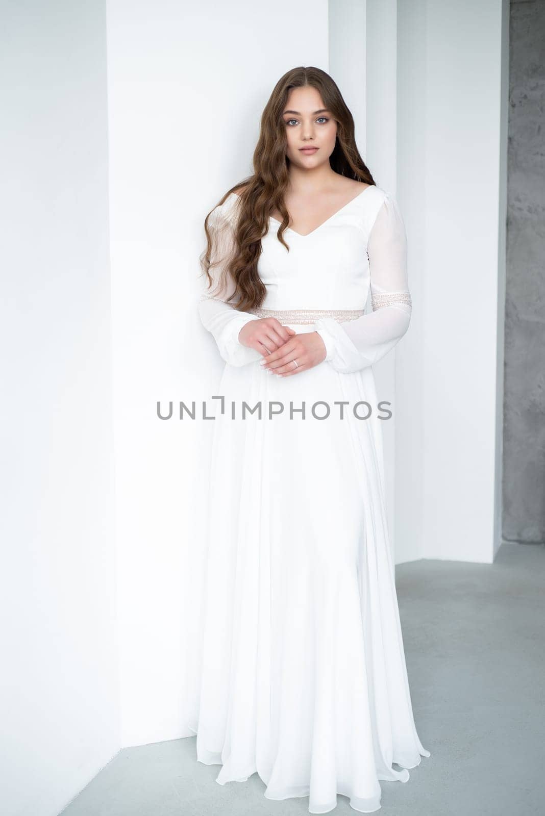 portrait of beautiful young woman in white wedding dress posing in studio