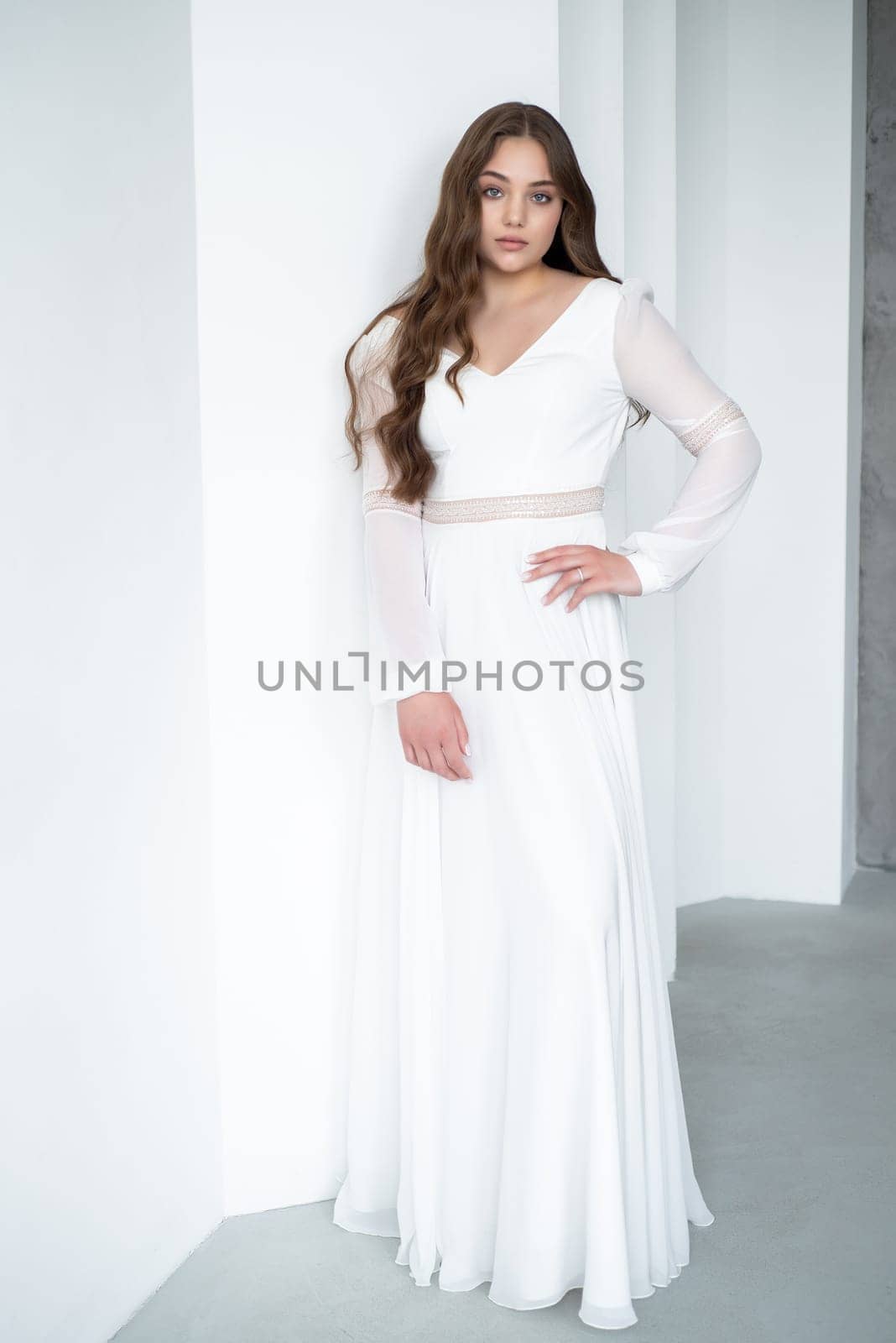 portrait of beautiful young woman in white wedding dress posing in studio