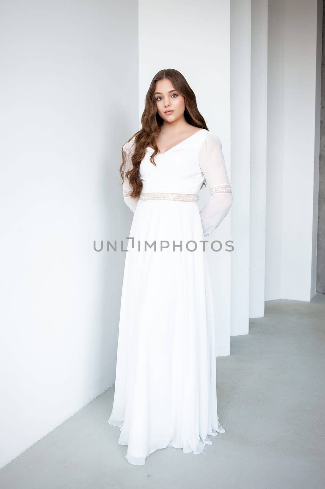 portrait of beautiful young woman in white wedding dress posing in studio