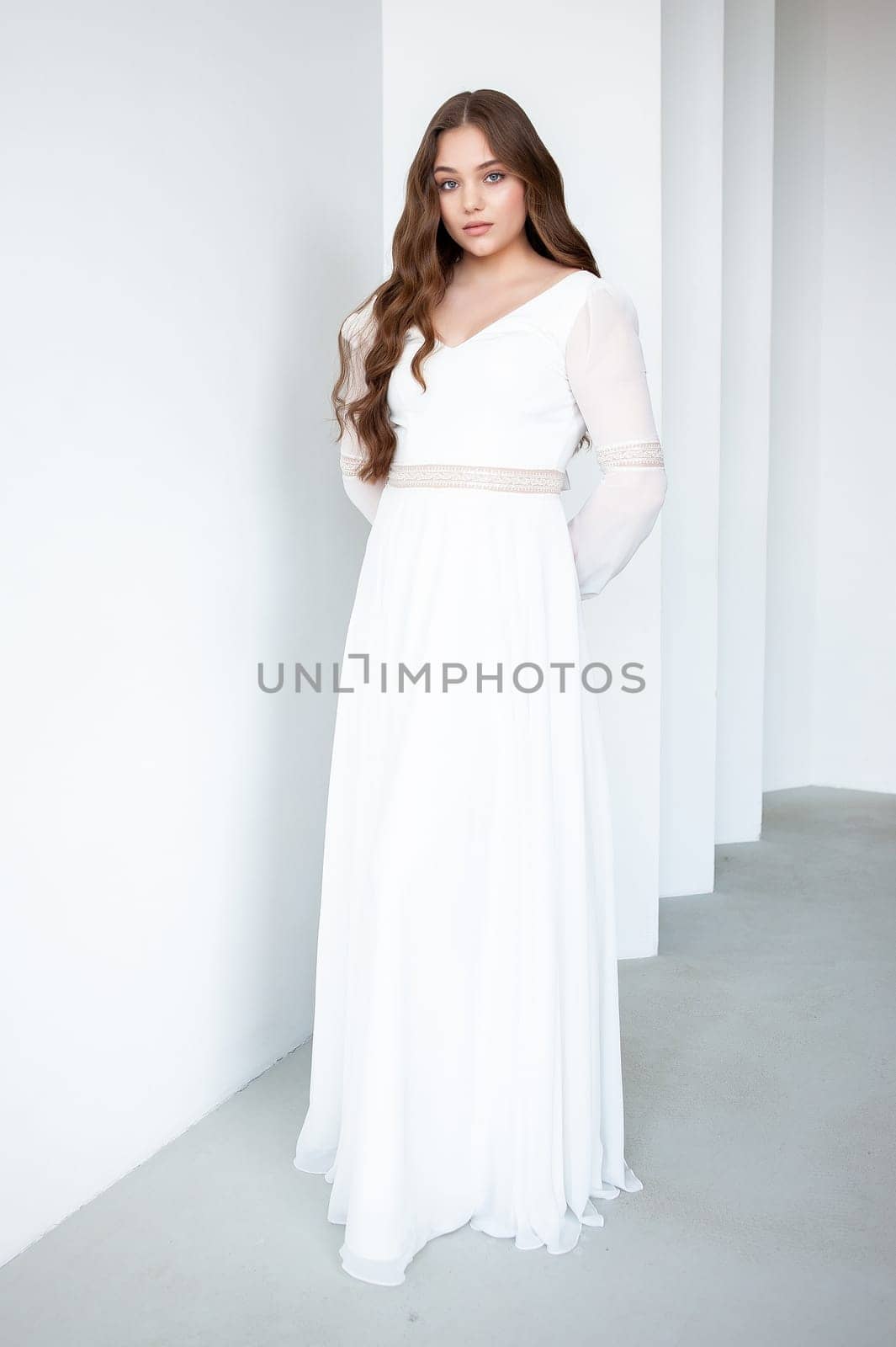 portrait of beautiful young woman in white wedding dress posing in studio