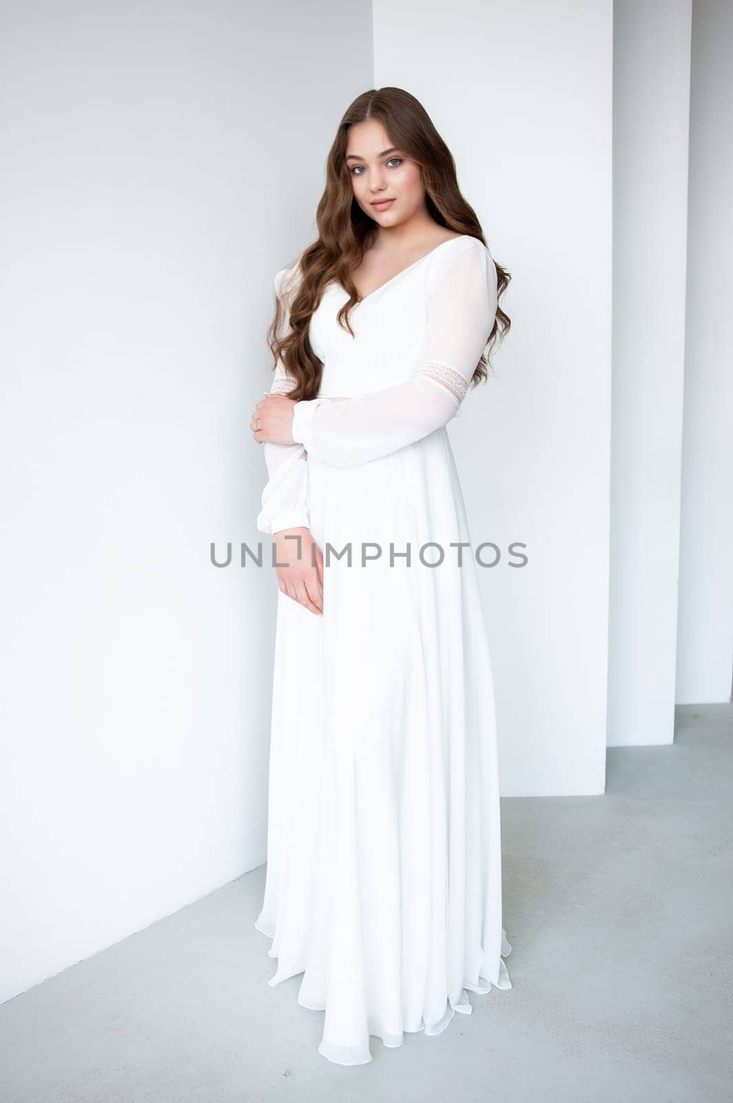 portrait of beautiful young woman in white wedding dress posing in studio