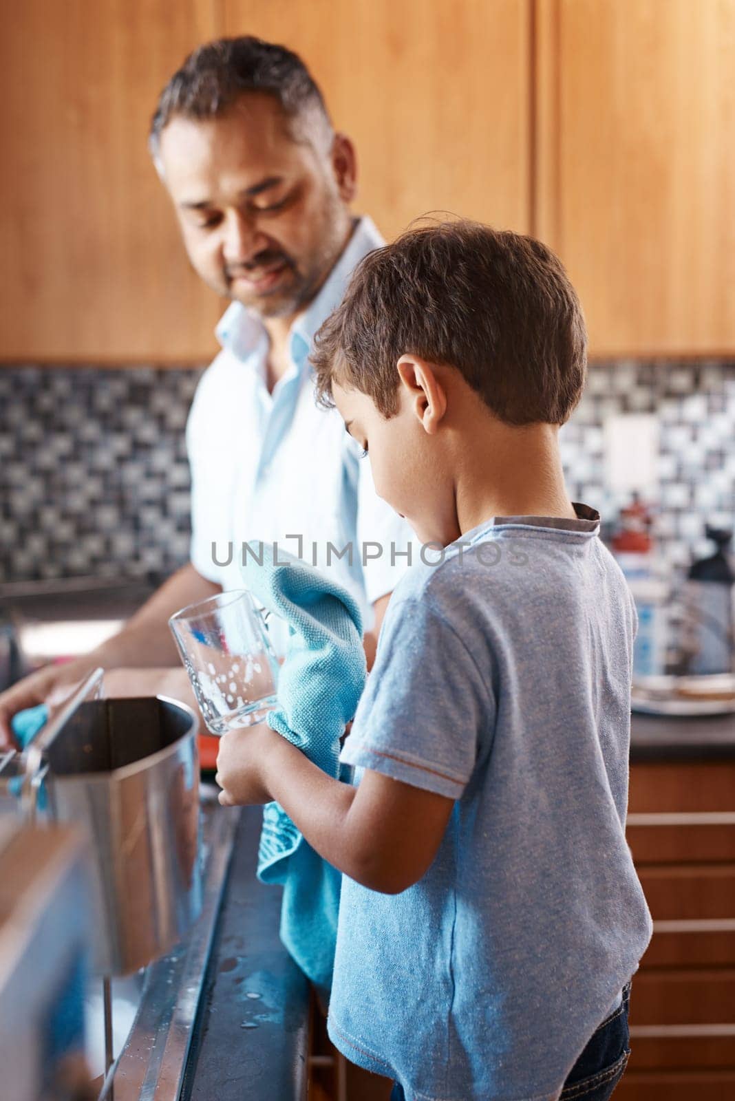 Child, help and father washing dishes in kitchen together for learning housekeeping at home. Teaching, hygiene and dad with boy kid cleaning glasses with cloth for chores and bonding at house