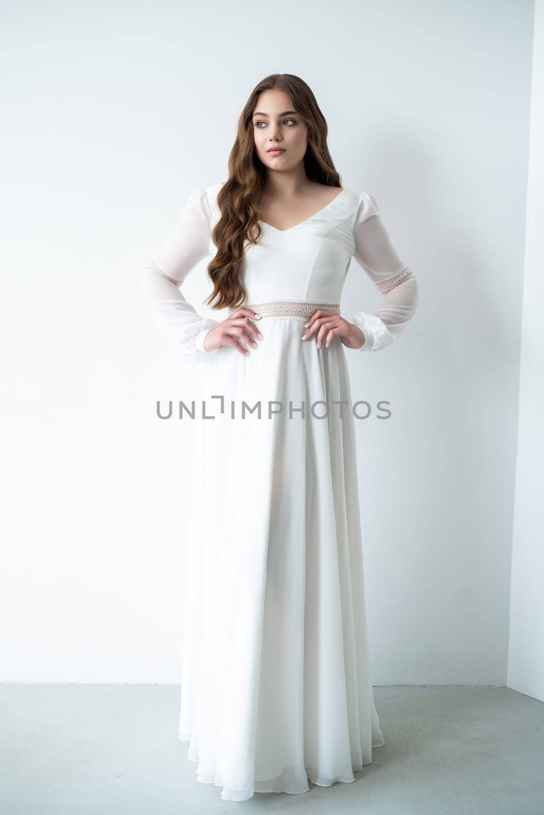 portrait of beautiful young woman in white wedding dress posing in studio