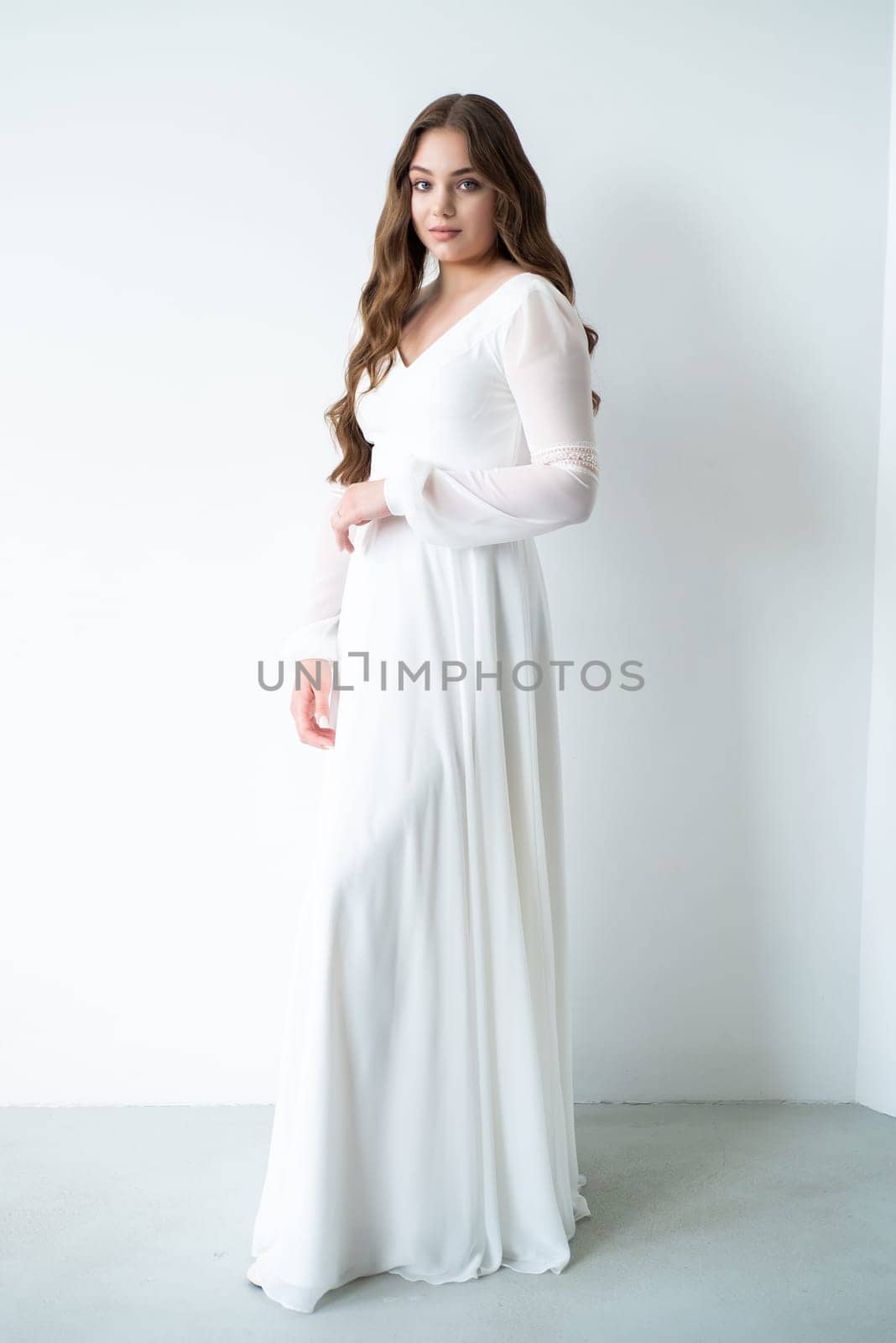 portrait of beautiful young woman in white wedding dress posing in studio