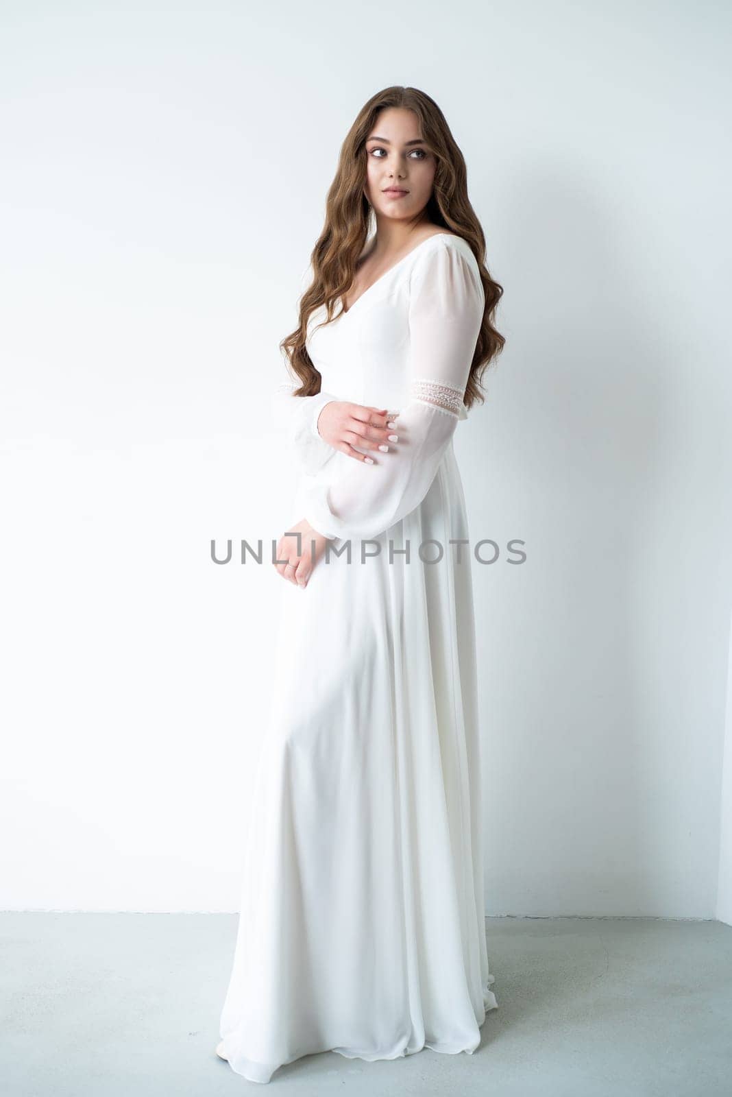 portrait of beautiful young woman in white wedding dress posing in studio