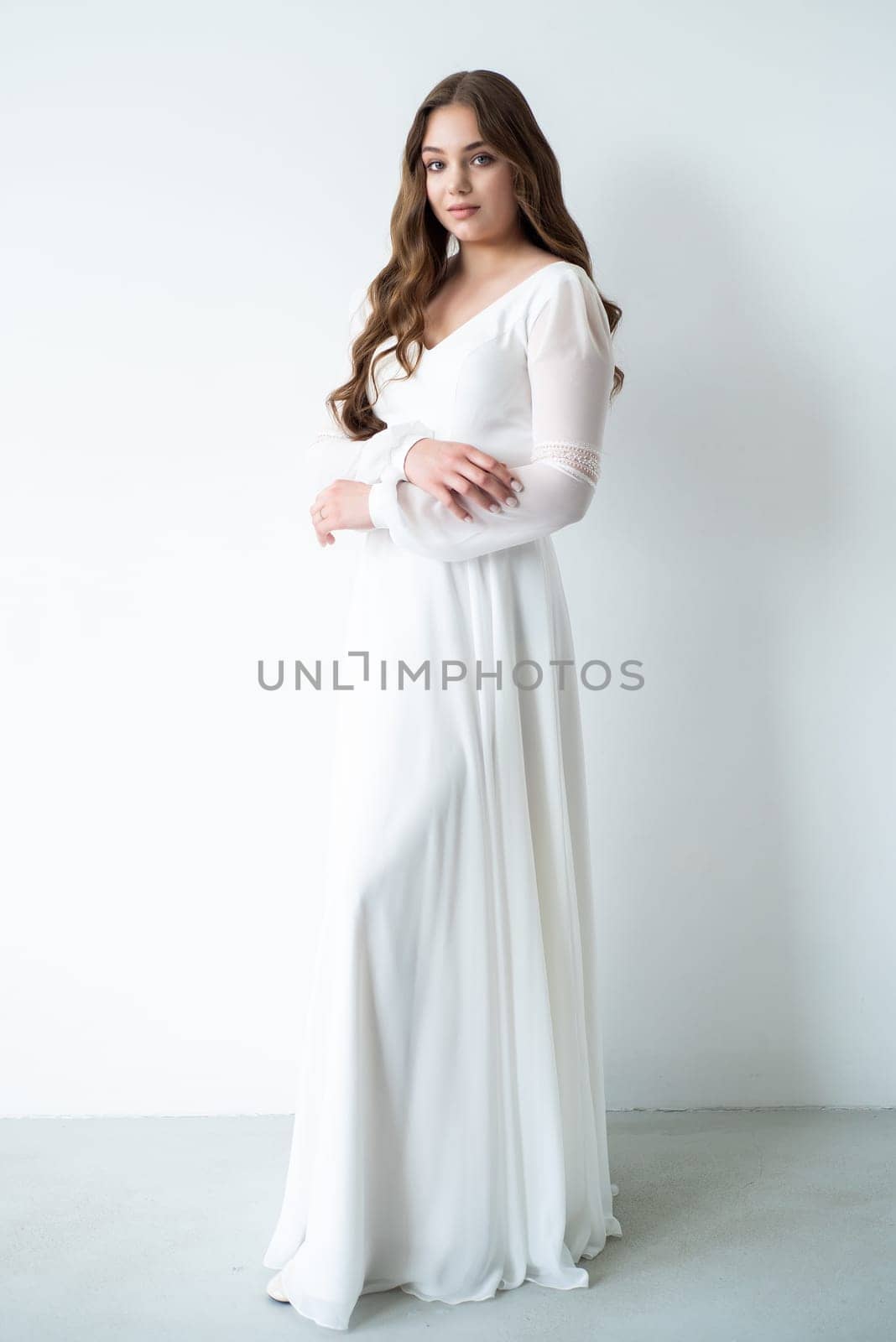 portrait of beautiful young woman in white wedding dress posing in studio