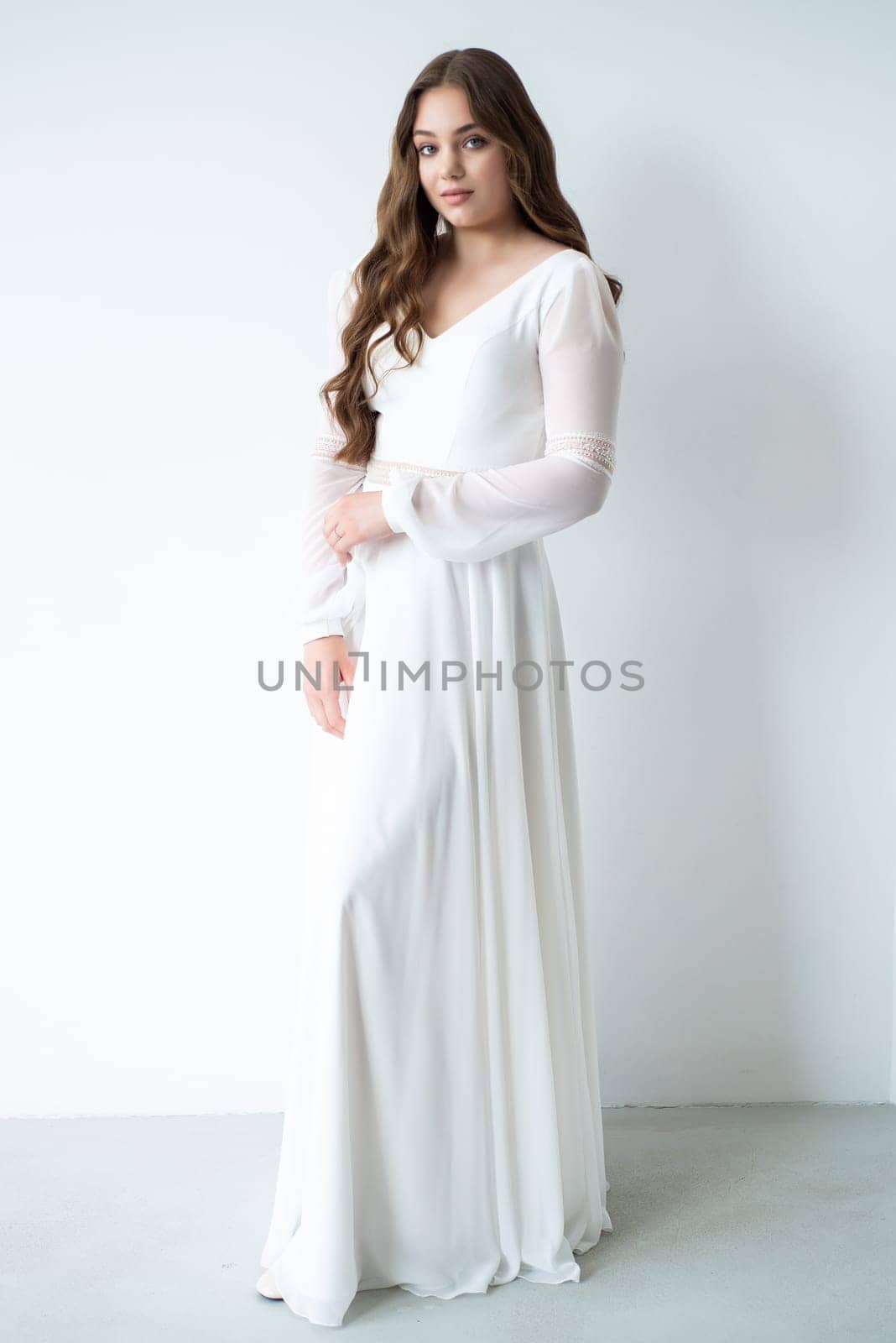 portrait of beautiful young woman in white wedding dress posing in studio