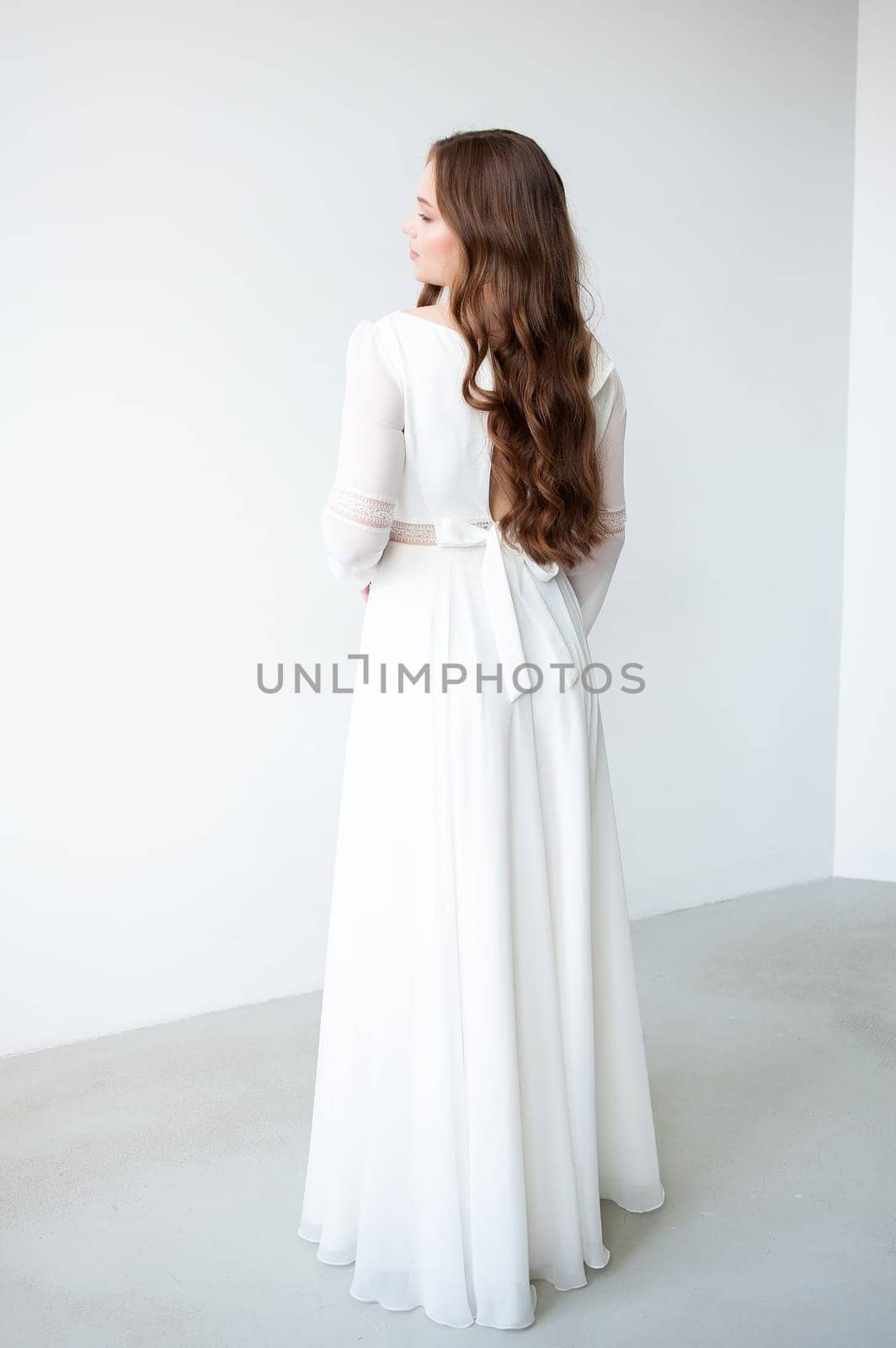 portrait of beautiful young woman in white wedding dress posing in studio