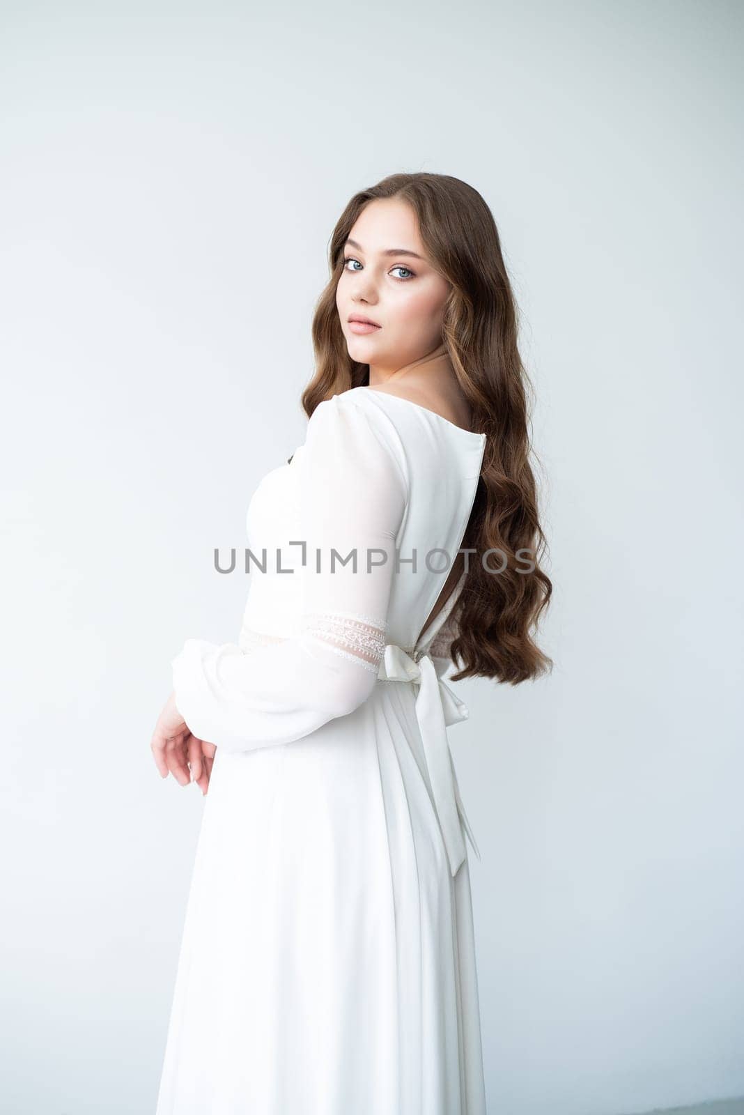 portrait of beautiful young woman in white wedding dress posing in studio