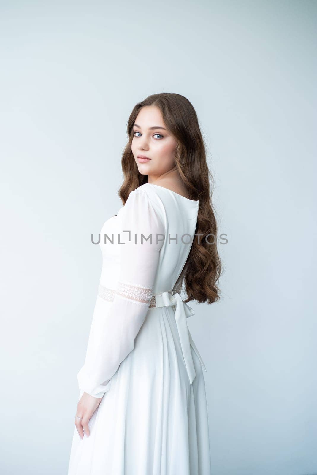 portrait of beautiful young woman in white wedding dress posing in studio