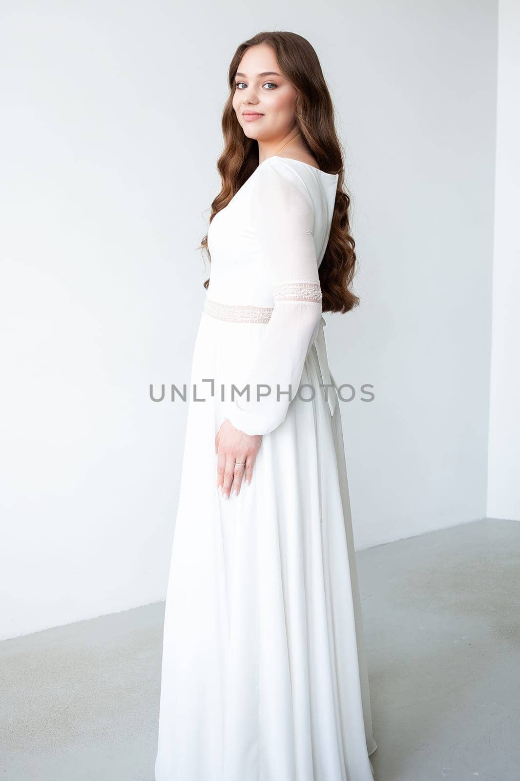 portrait of beautiful young woman in white wedding dress posing in studio