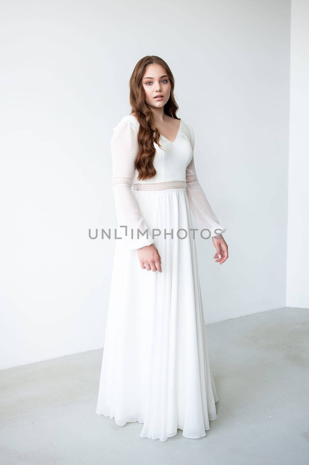 portrait of beautiful young woman in white wedding dress posing in studio