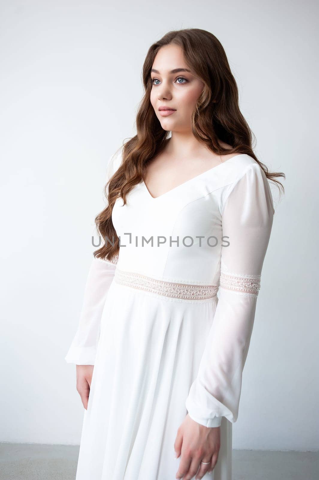 portrait of beautiful young woman in white wedding dress posing in studio