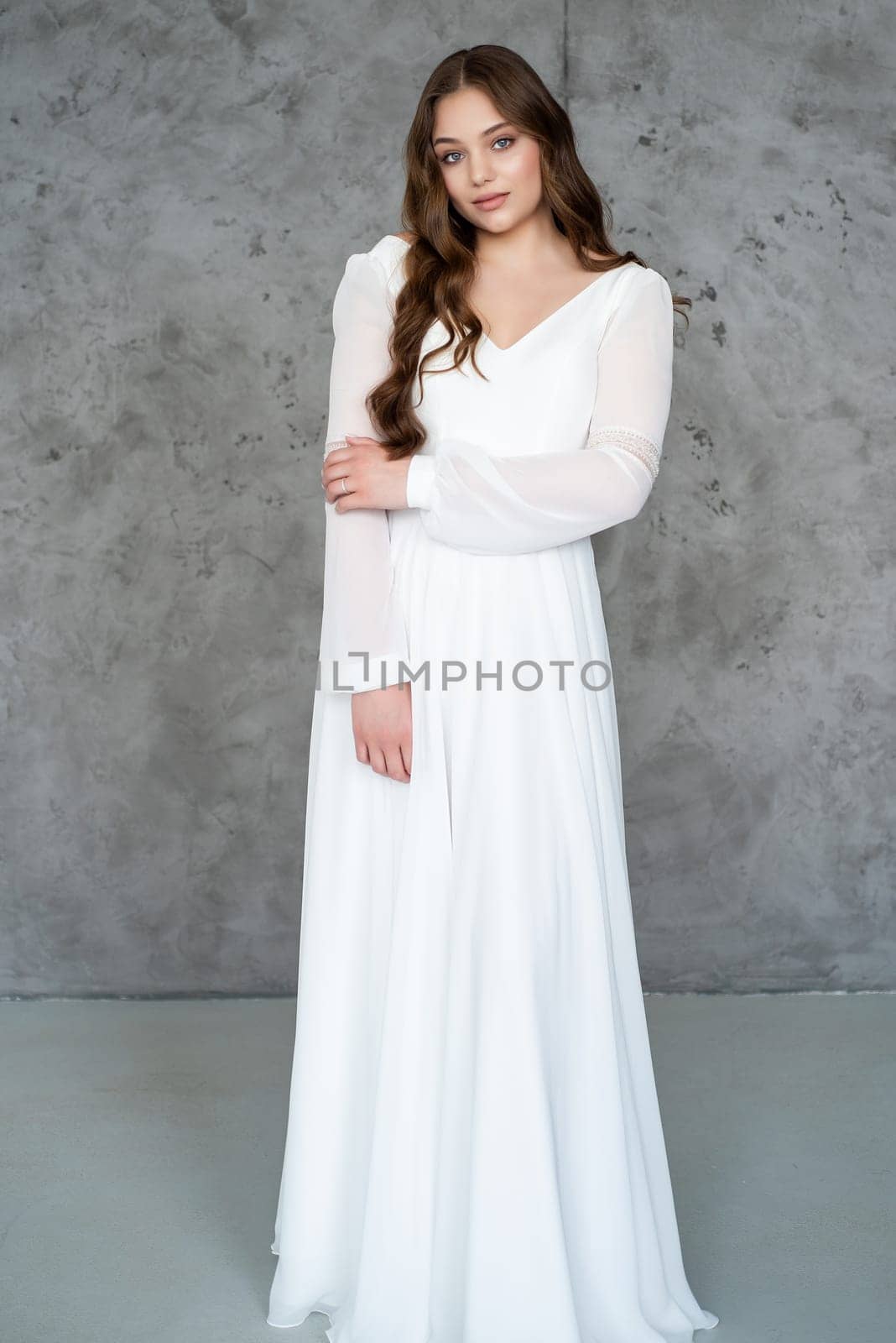 portrait of beautiful young woman in white wedding dress posing in studio