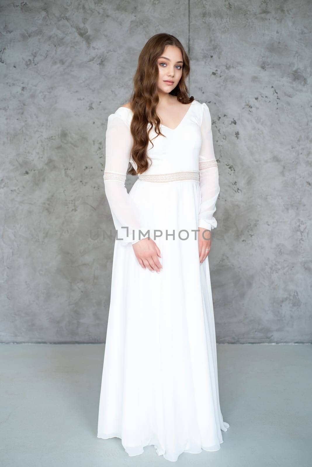 portrait of beautiful young woman in white wedding dress posing in studio