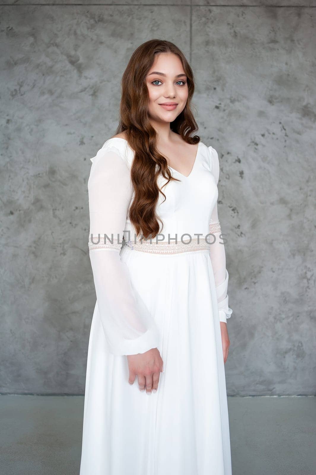 portrait of beautiful young woman in white wedding dress posing in studio