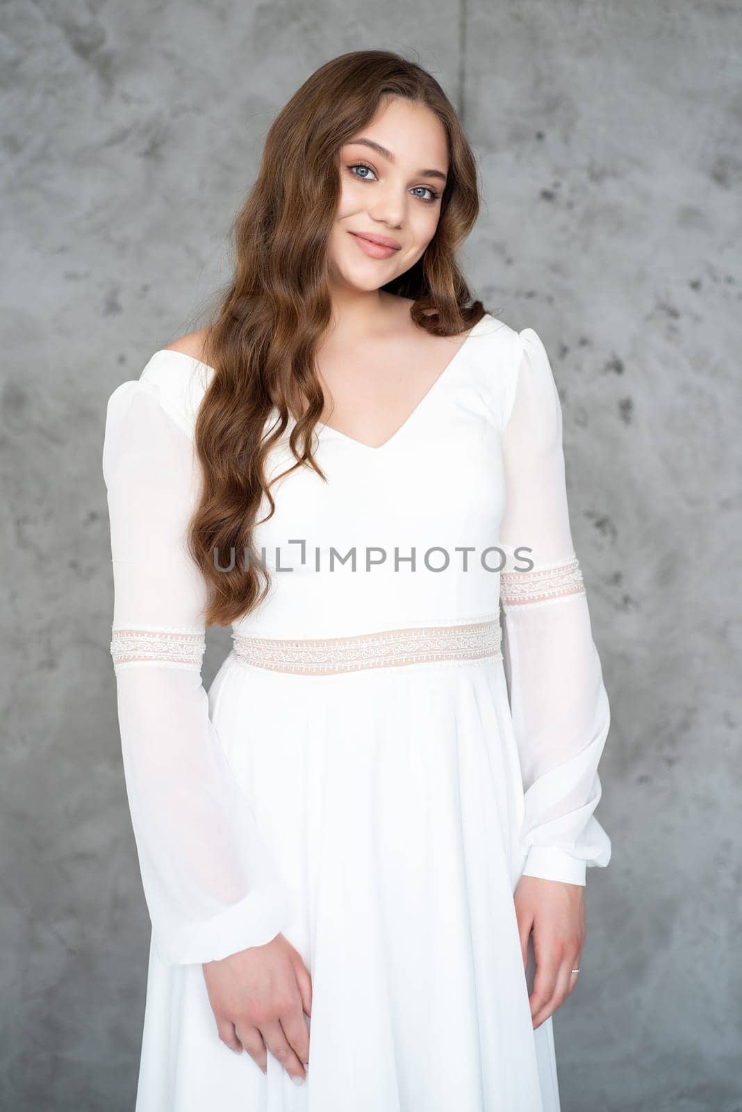 portrait of beautiful young woman in white wedding dress posing in studio