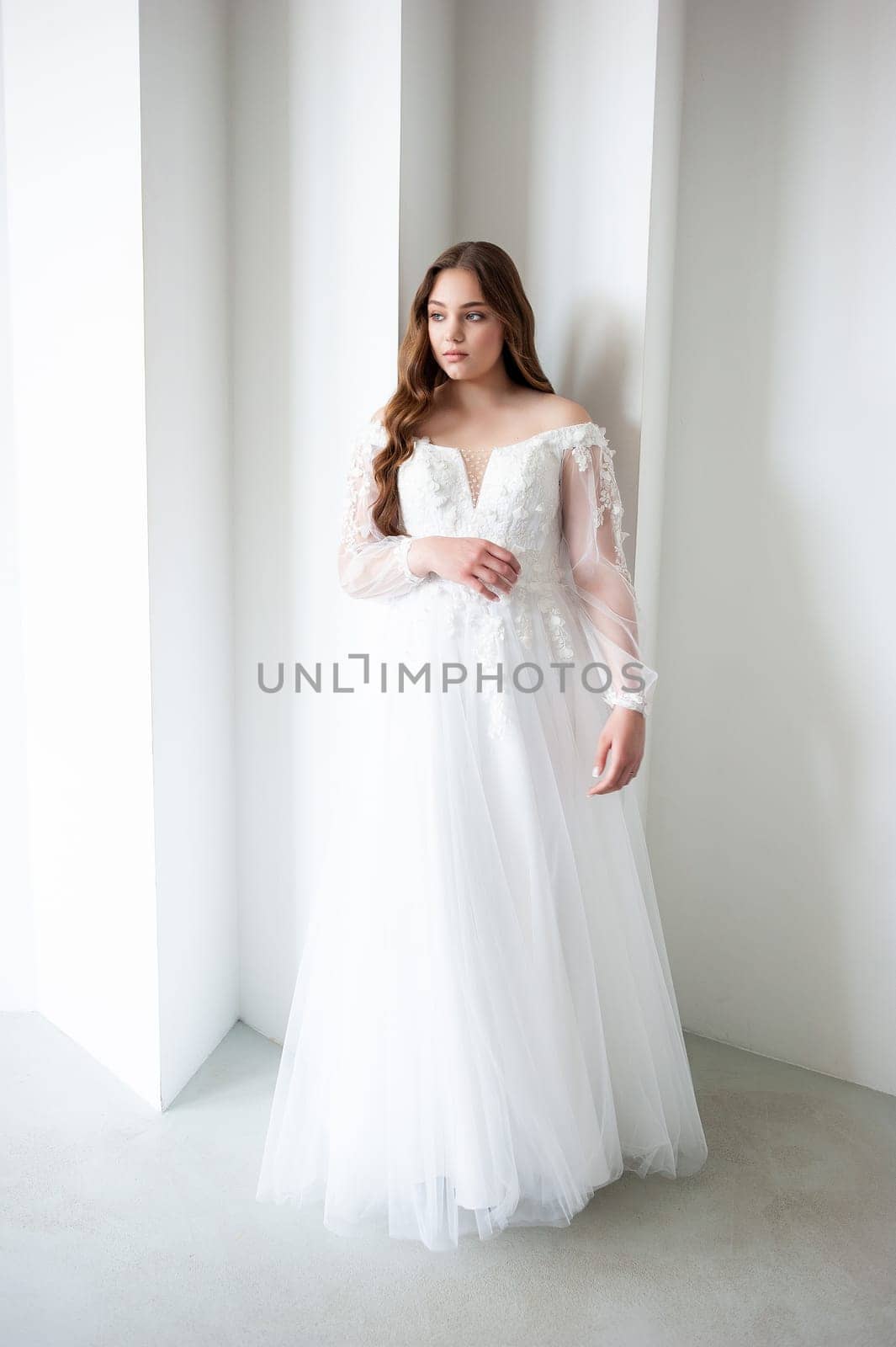 portrait of beautiful young woman in white wedding dress posing in studio