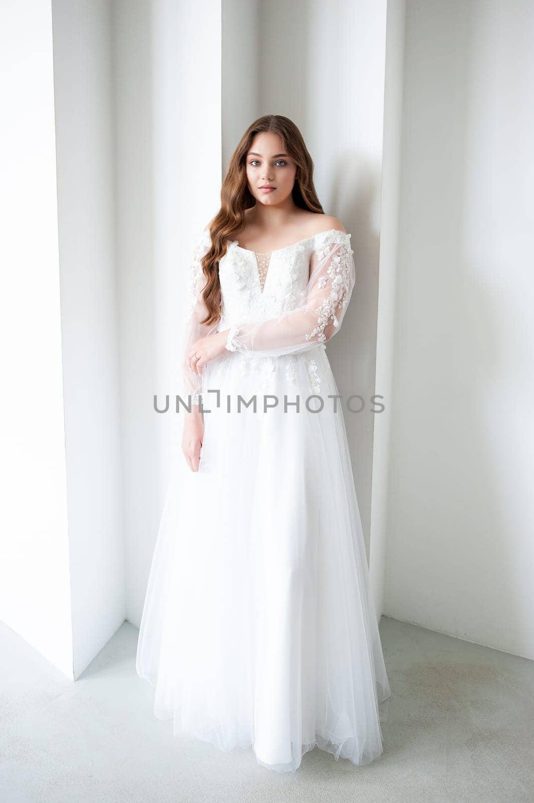 portrait of beautiful young woman in white wedding dress posing in studio