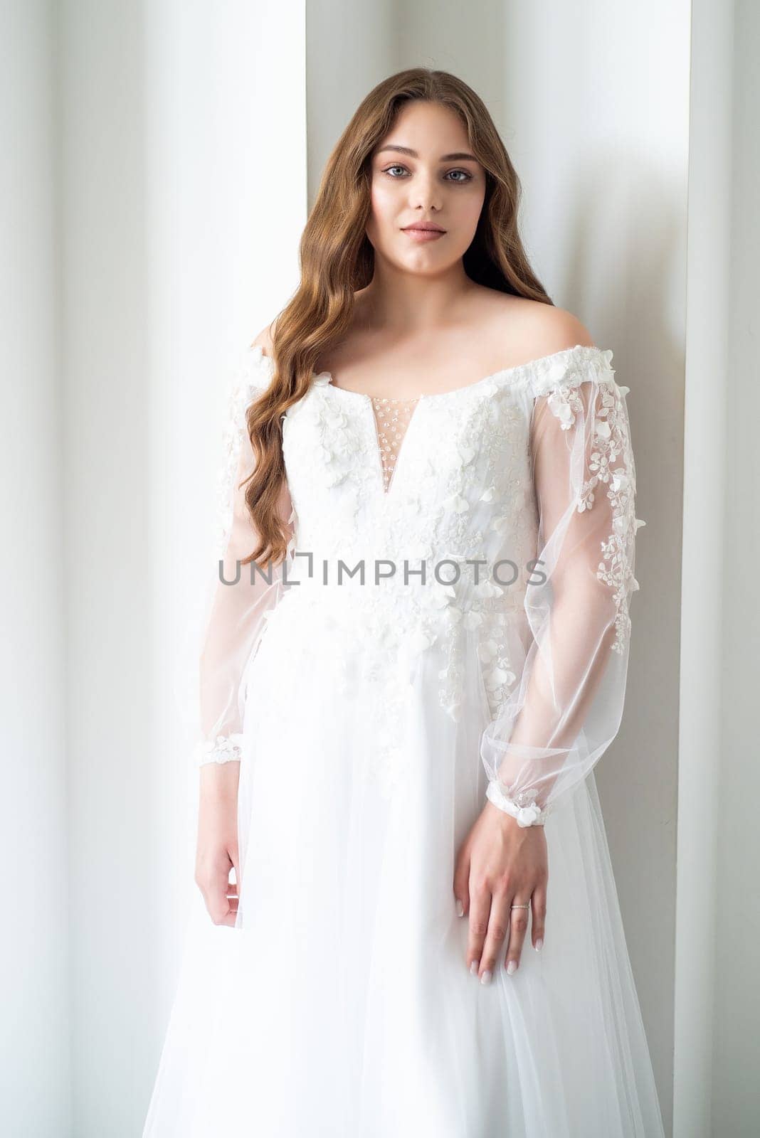 portrait of beautiful young woman in white wedding dress posing in studio