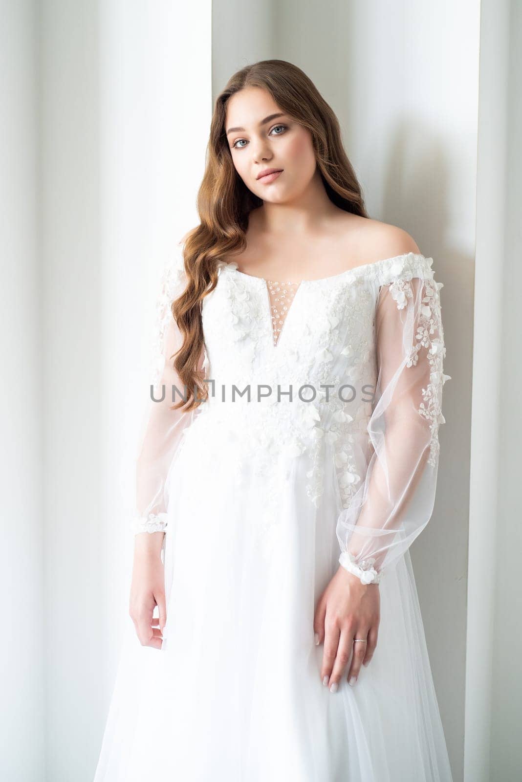 portrait of beautiful young woman in white wedding dress posing in studio