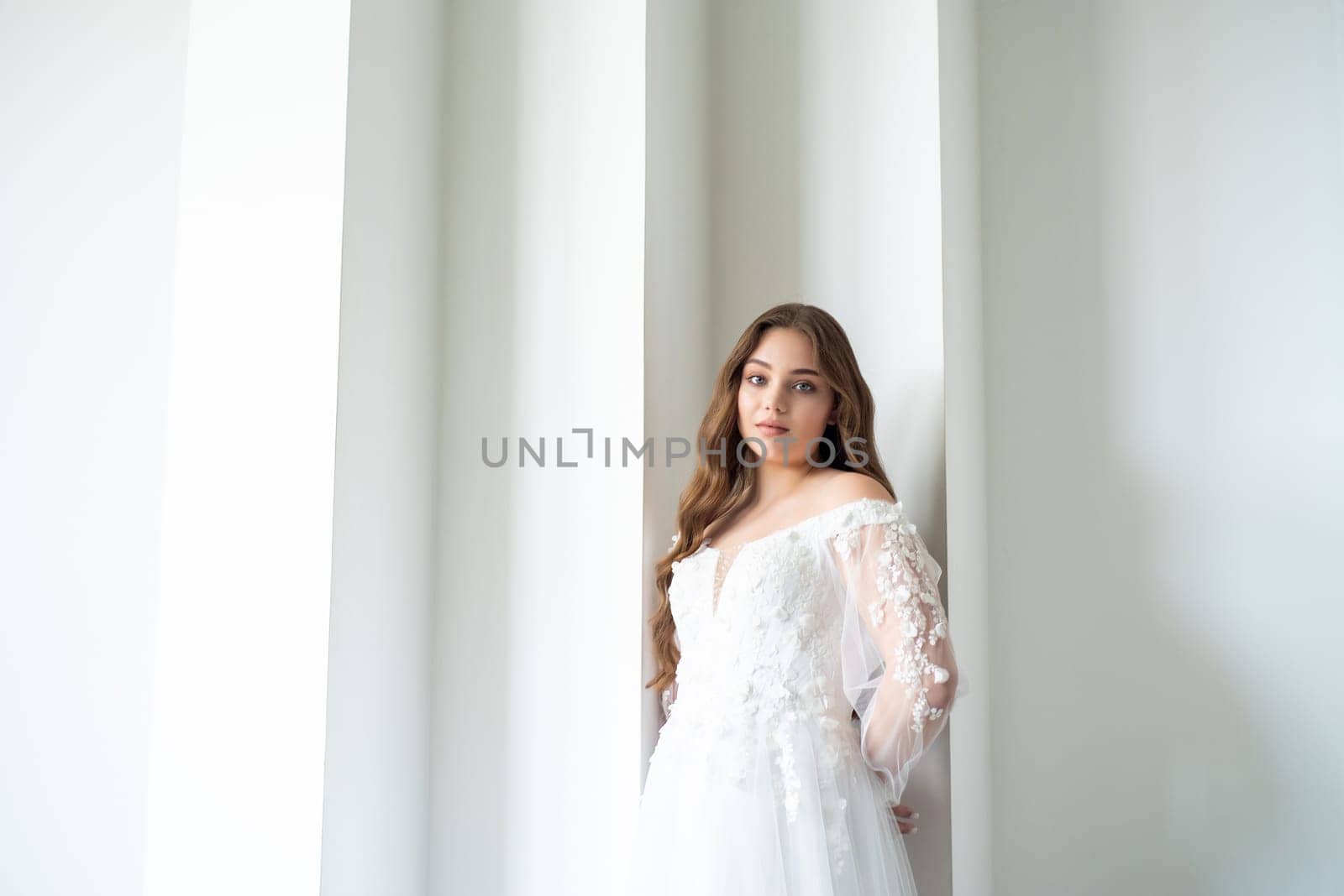 portrait of beautiful young woman in white wedding dress posing in studio. by OleksandrLipko