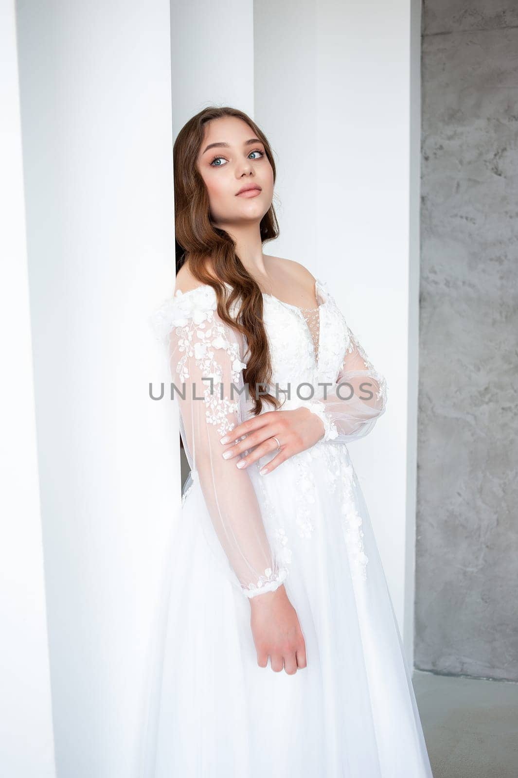 portrait of beautiful young woman in white wedding dress posing in studio