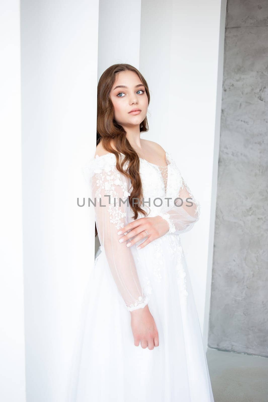 portrait of beautiful young woman in white wedding dress posing in studio