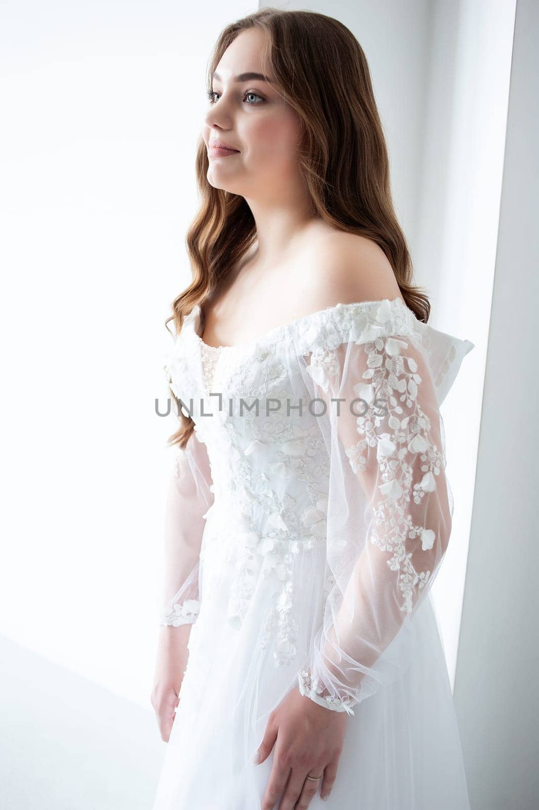 portrait of beautiful young woman in white wedding dress posing in studio