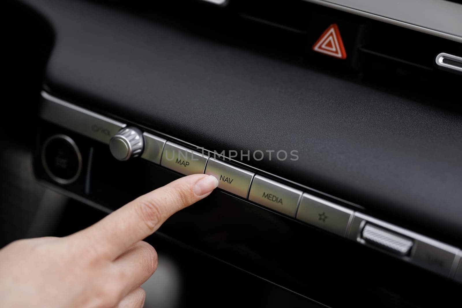 Close-up view of car interior. View of car navigation button. Driver pressing navigation button of electric car. GPS Navigation map system screen in the car for travel.