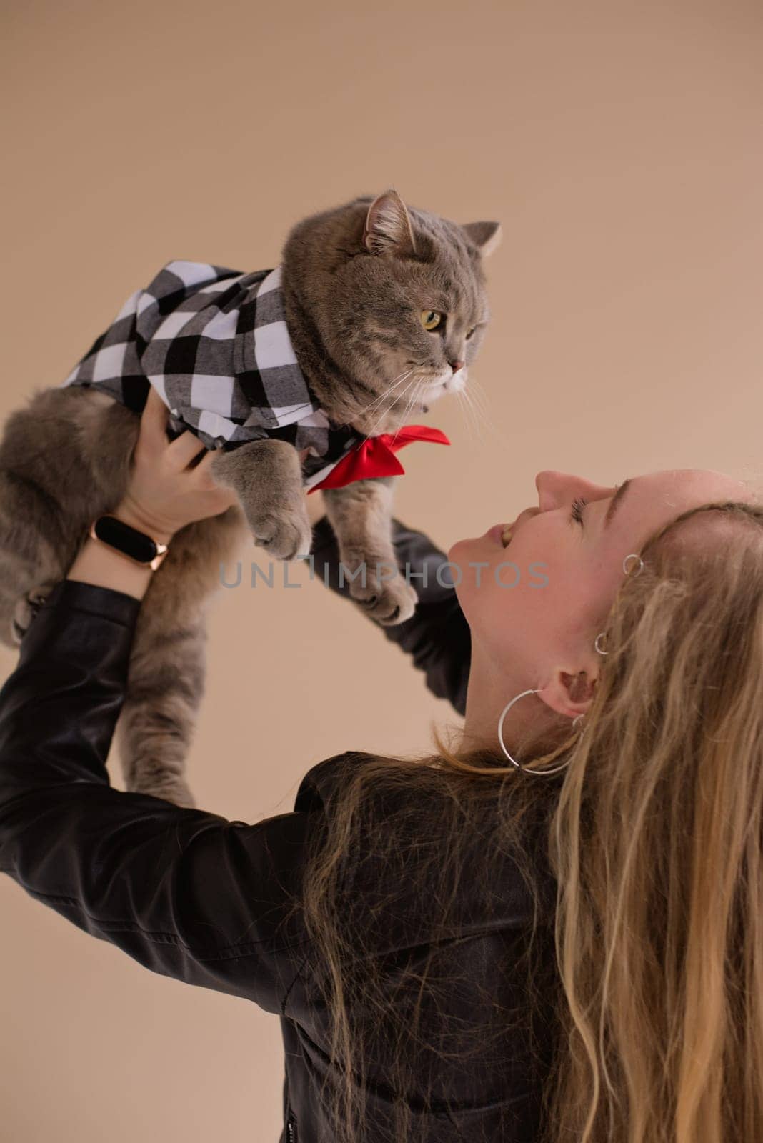 A woman natural blonde long hair smiling in a black clothes stand, sitting on photo studio. girl with pet scottish straight cat. portrait , vertical, close up