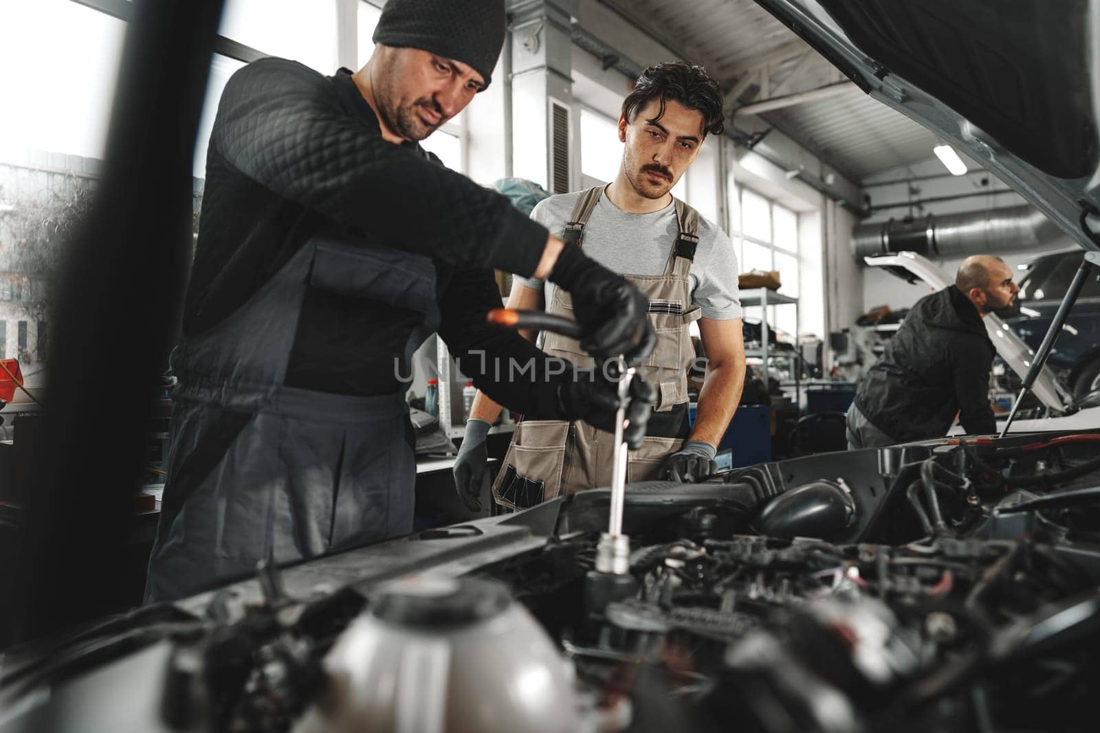 Two male mechanics repairing car in car service by Fabrikasimf