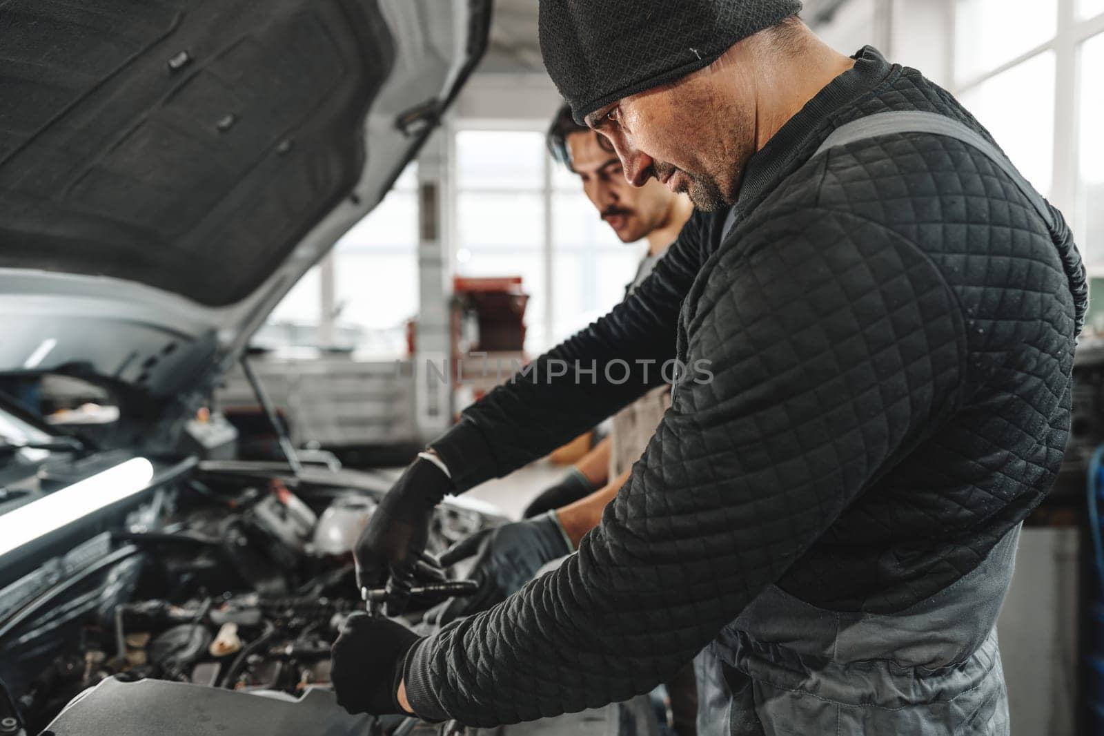 Two male mechanics repairing car in car service close up