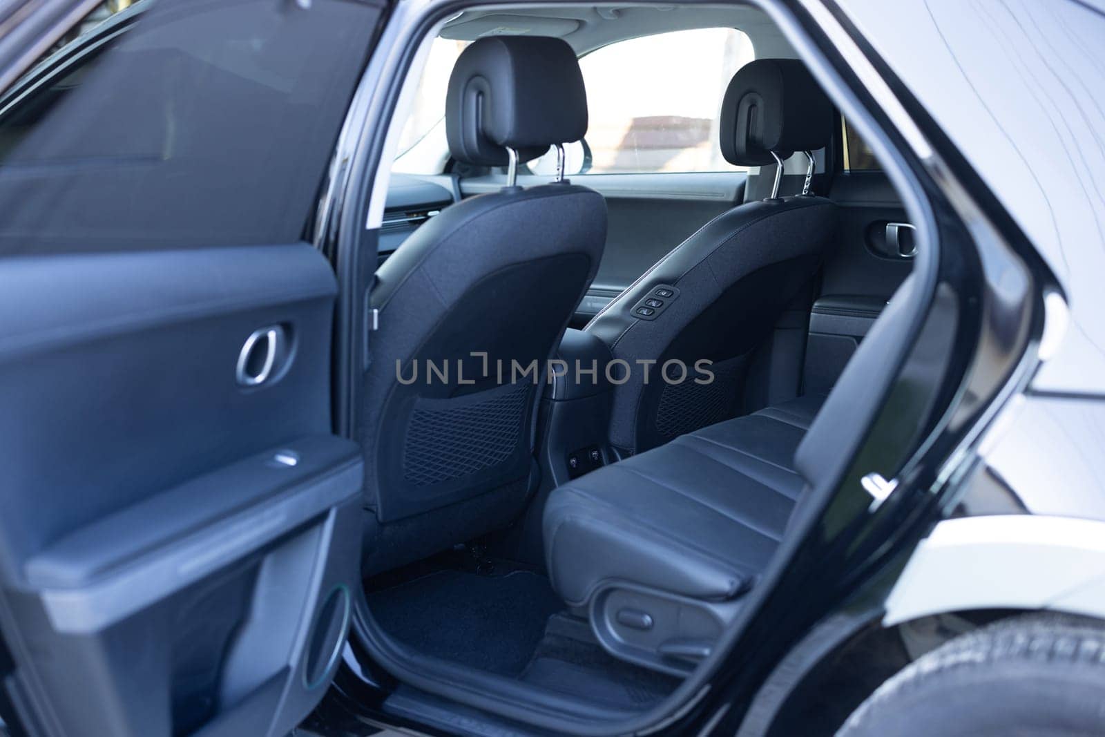 Rear leather passenger seats in modern lux electric car. Black leather car passenger seat. Control unit with electric seat adjustment for rear passengers in luxury car. Modern car interior detail by uflypro