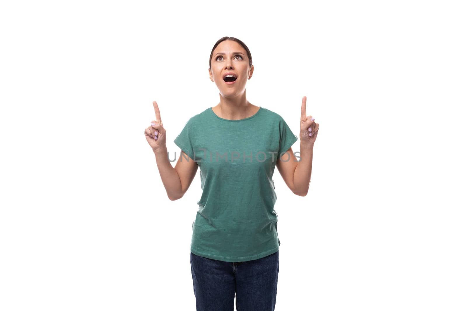 active smiling young caucasian brunette woman in a green t-shirt points with her hand at the space for advertising by TRMK