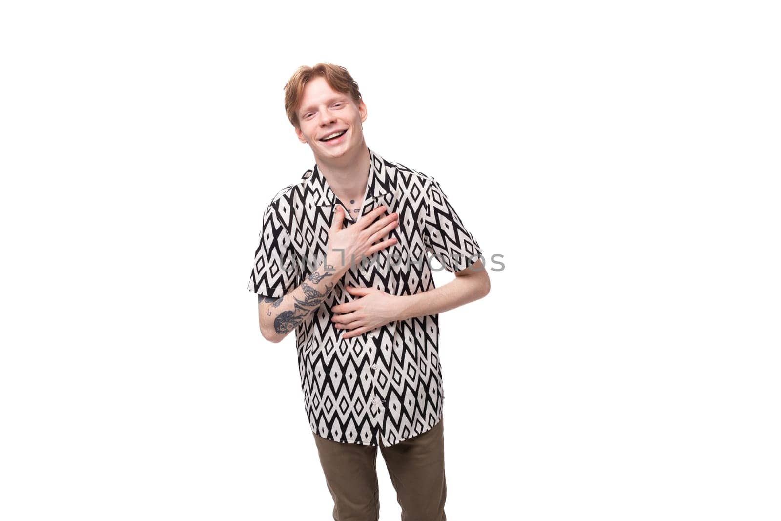 young friendly cute european man with golden hair is dressed in a stylish black and white shirt on a studio background with copy space.