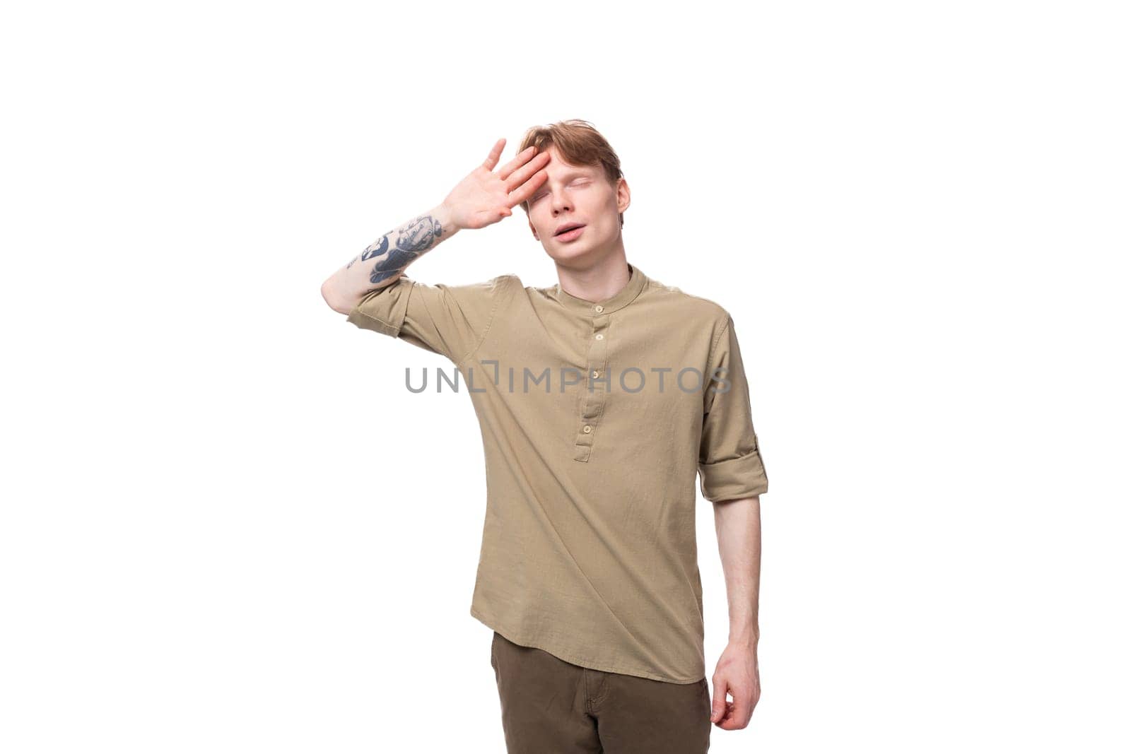 a young European guy with red hair is dressed in a fashionable beige shirt and brown trousers by TRMK