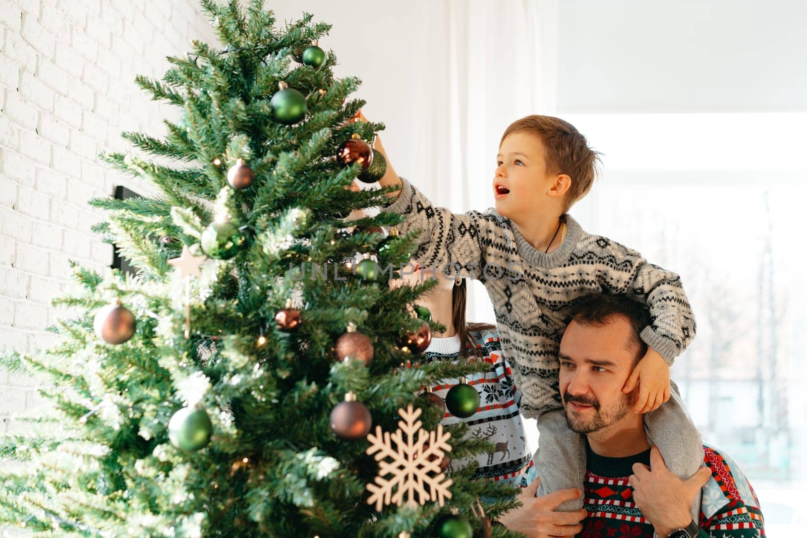 Young dad and his son celebrate Christmas together at home by Fabrikasimf
