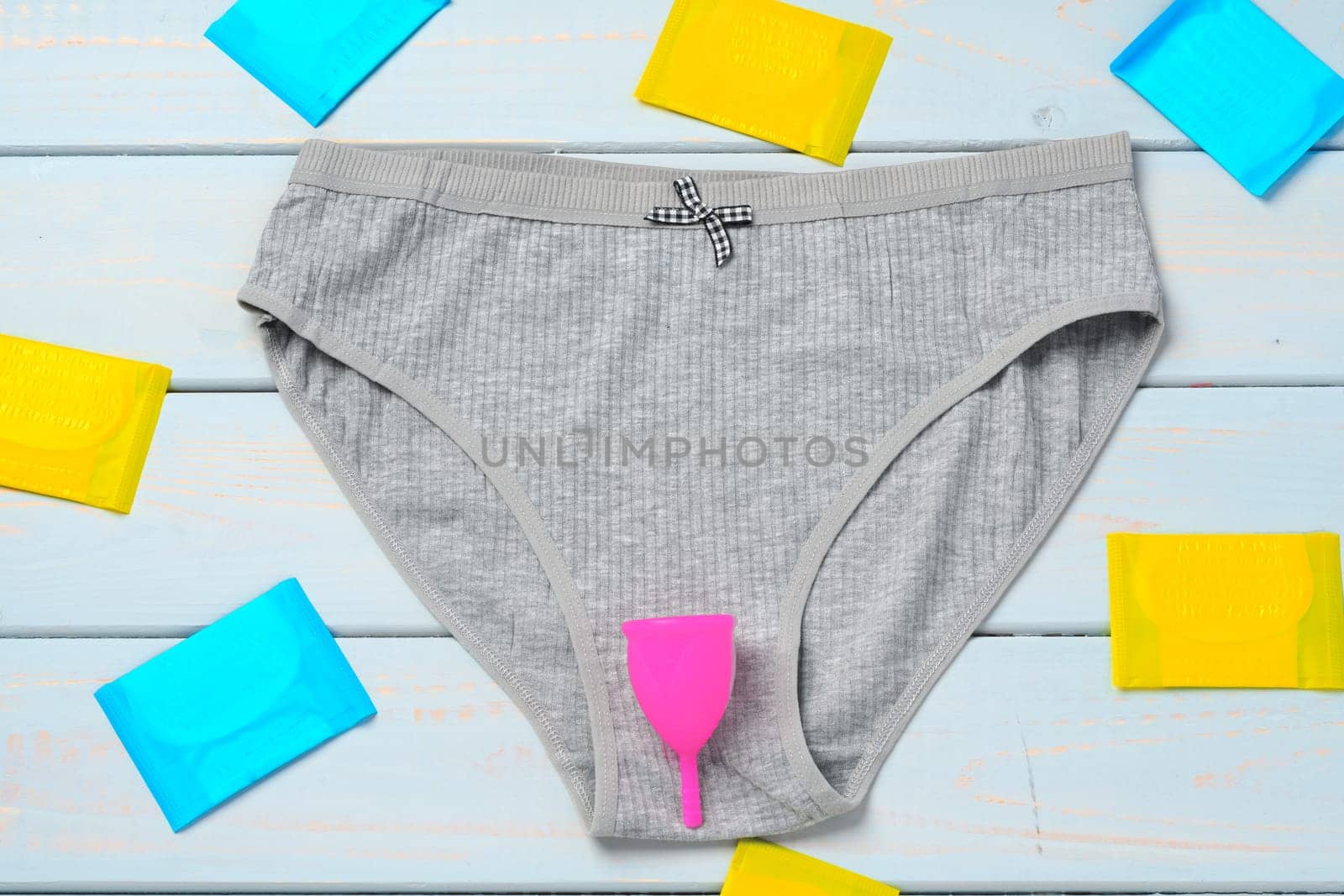 Menstrual cup and panties on wooden background, top view