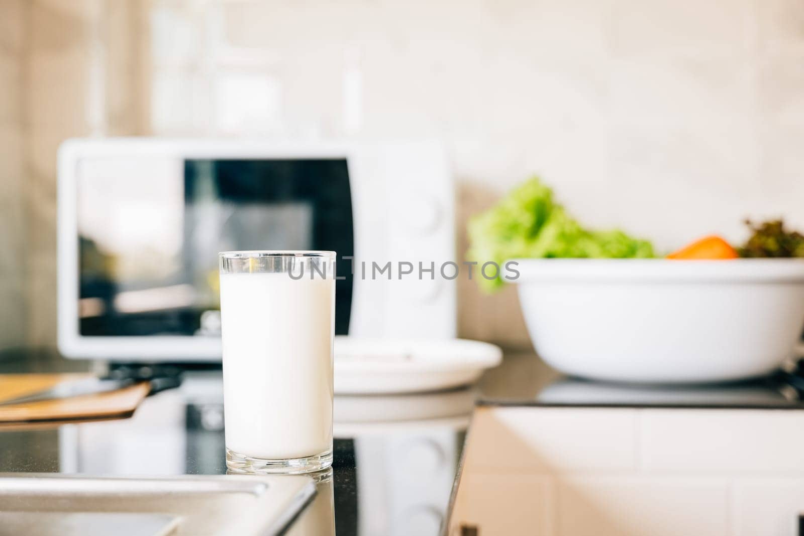 Fresh cow milk in glass on clean kitchen counter. Space for text or product display. Morning protein drink for healthy diet. by Sorapop
