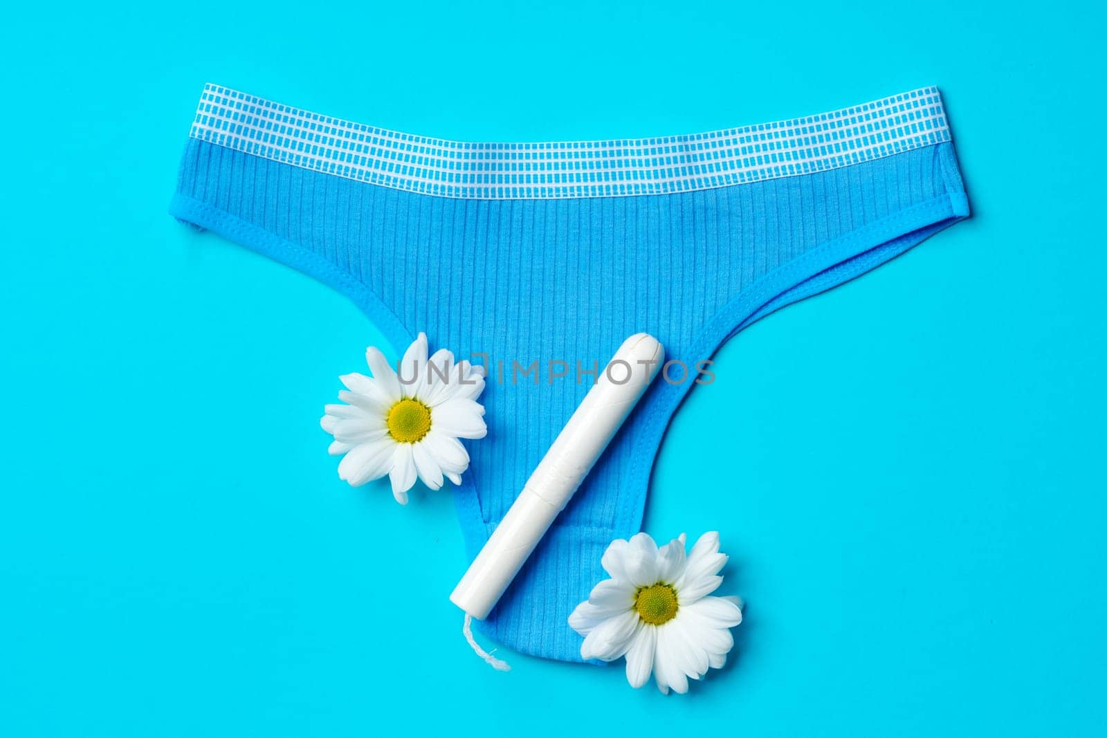Women's panties with sanitary tampon on color background top view