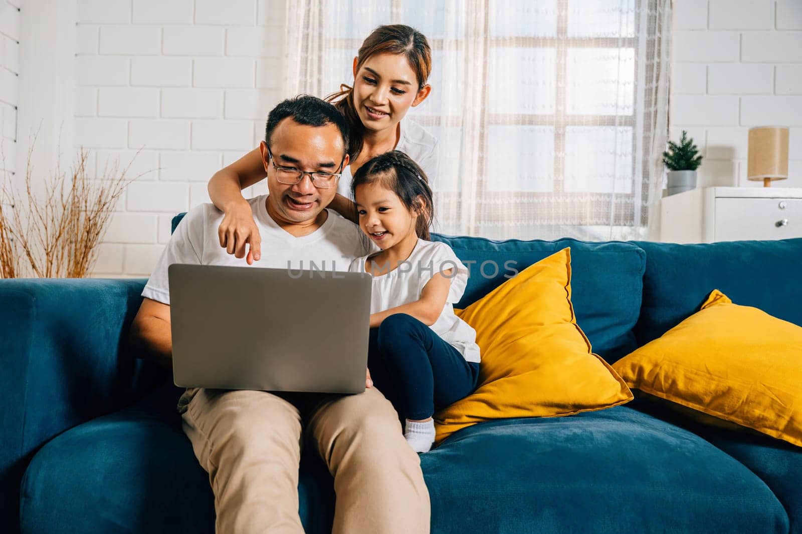 Parents and kids gathered on the couch with a laptop finding happiness in their modern family time by Sorapop