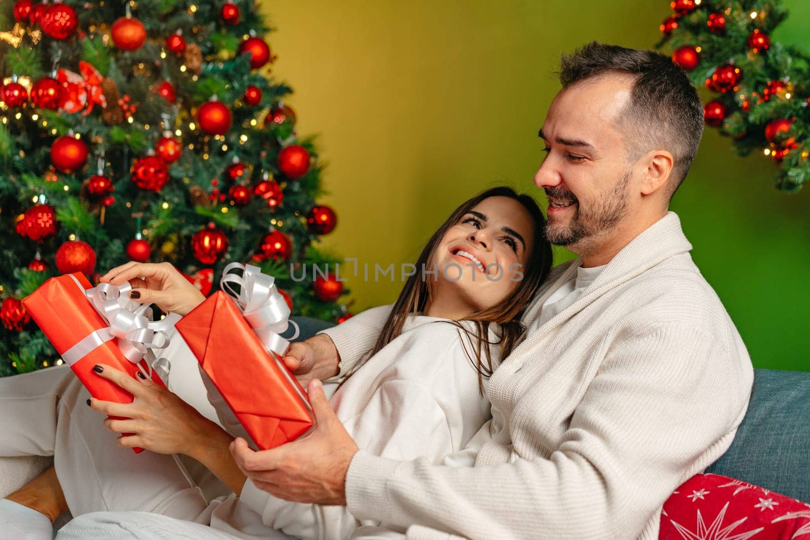 Happy young couple sitting on sofa on Christmas eve at home close up